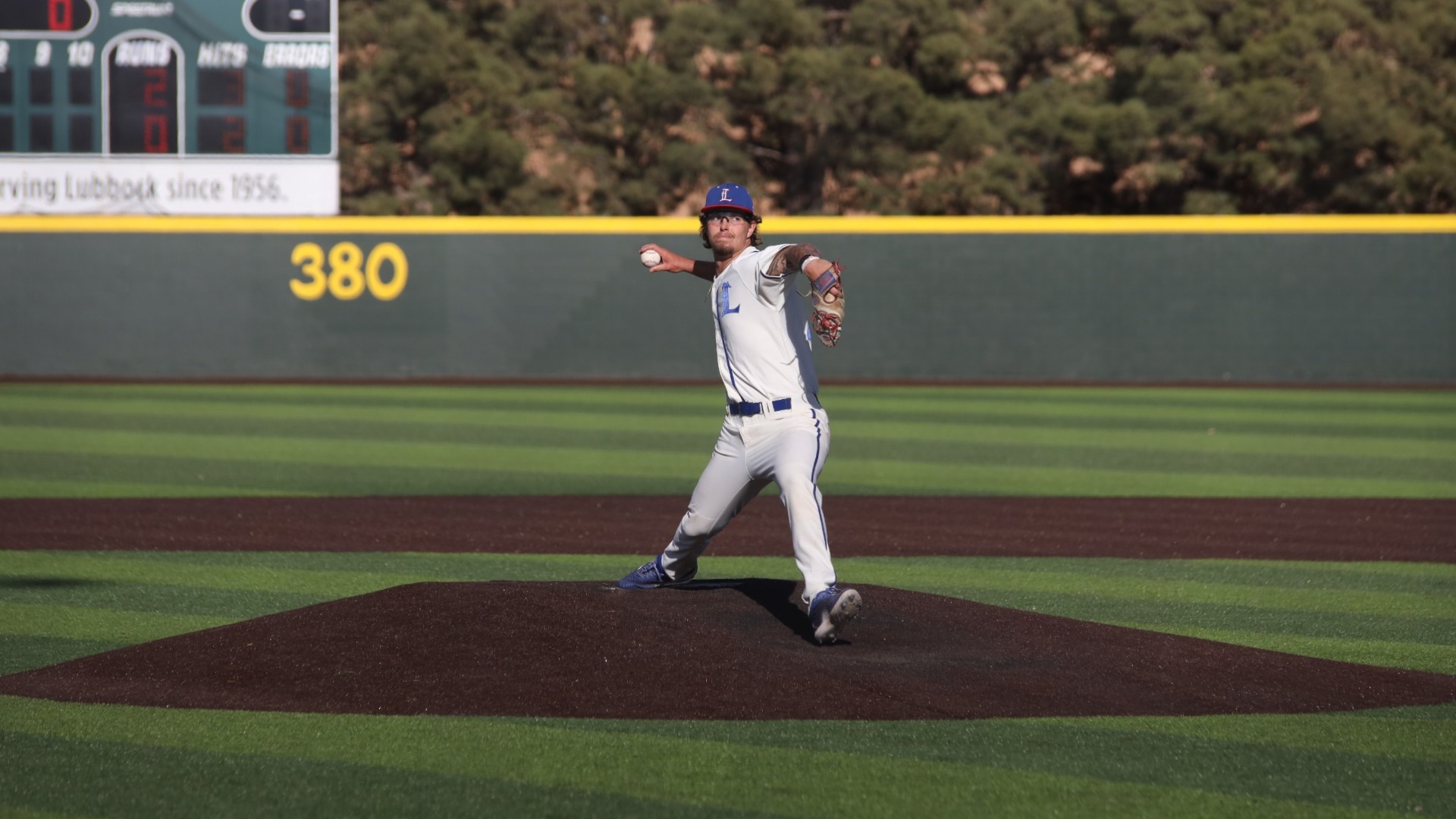 This is a photograph of Lubbock Christian pitcher Dakota McCaskill (white jersey, #34) throwing a pitch off the mound during a game at Hays Field. 