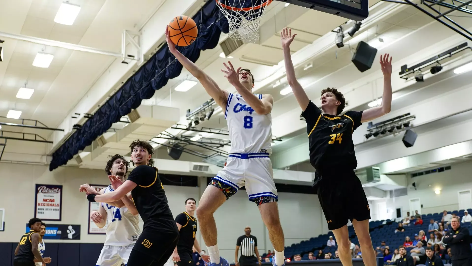 This is a photo of Lubbock Christian forward Amondo Miller Jr. shooting a layup around a Black Hills State defender during a game at the Burg Center.