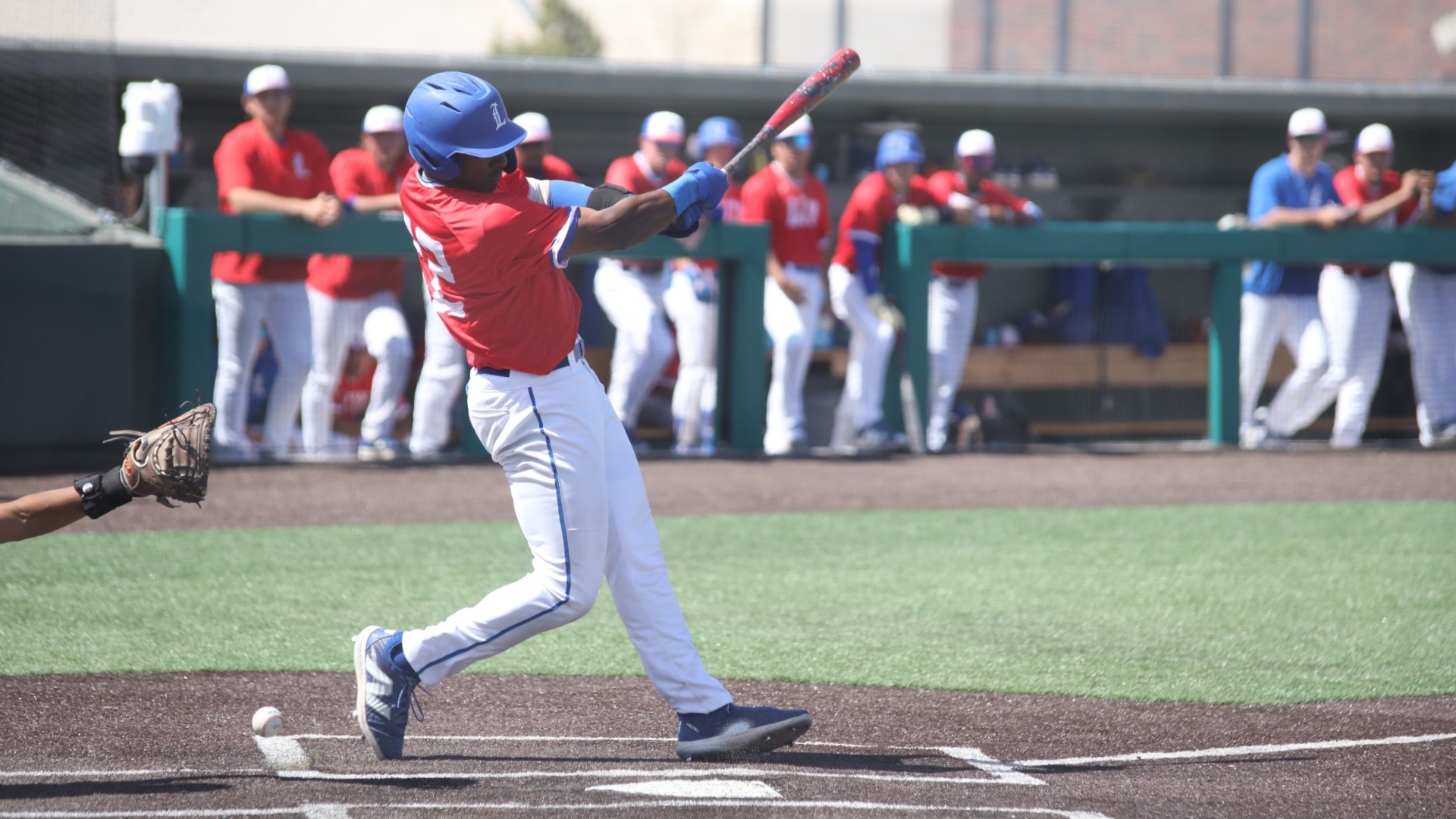 This is a photo of Freddie Nolen (red jersey, 22) hitting a baseball during a game at Hays Field. 