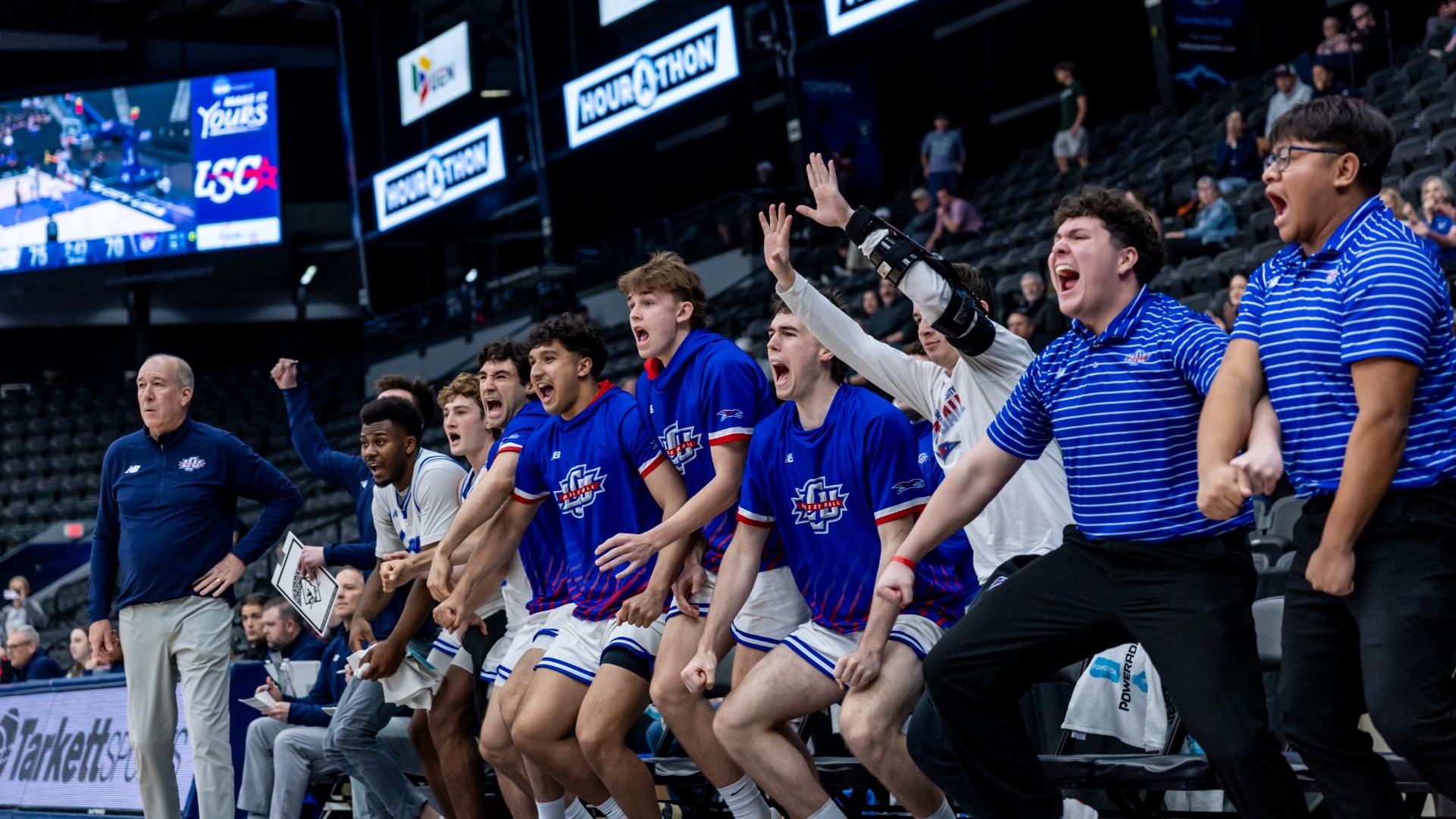 Players and coaches on the Lubbock Christian men's basketball bench celebrate after a made basket by the Chaps. 