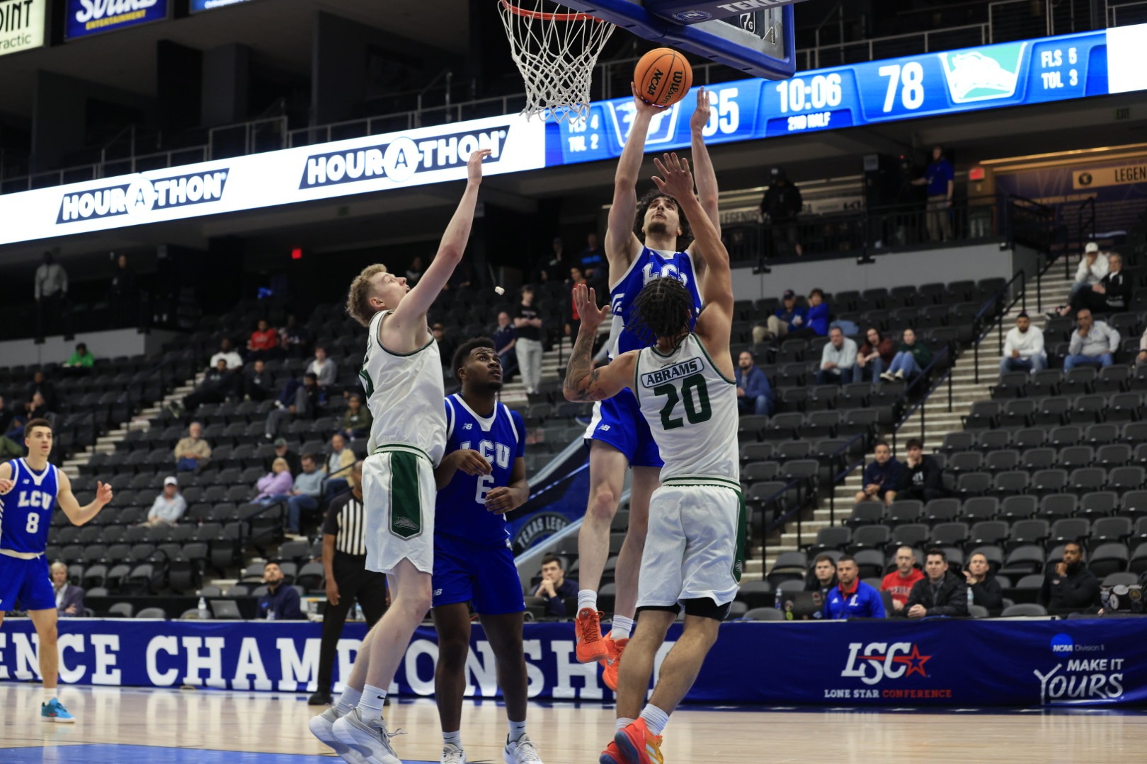This is an photo graph of Antonio Pusateri (blue jersey, #24) shooting a layup over Eastern New Mexico defenders. 