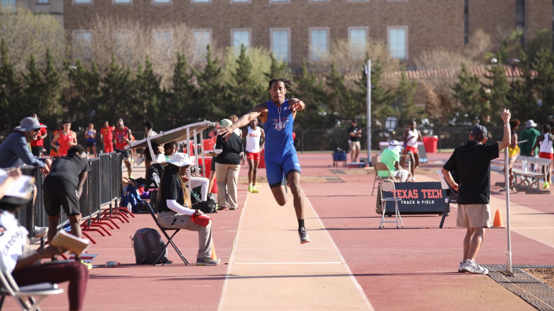 This is a photo of Lubbock Christian track and field athlete Maurice Gray (blue uniform) competing in the triple jump at a meet hosted by Texas Tech. 