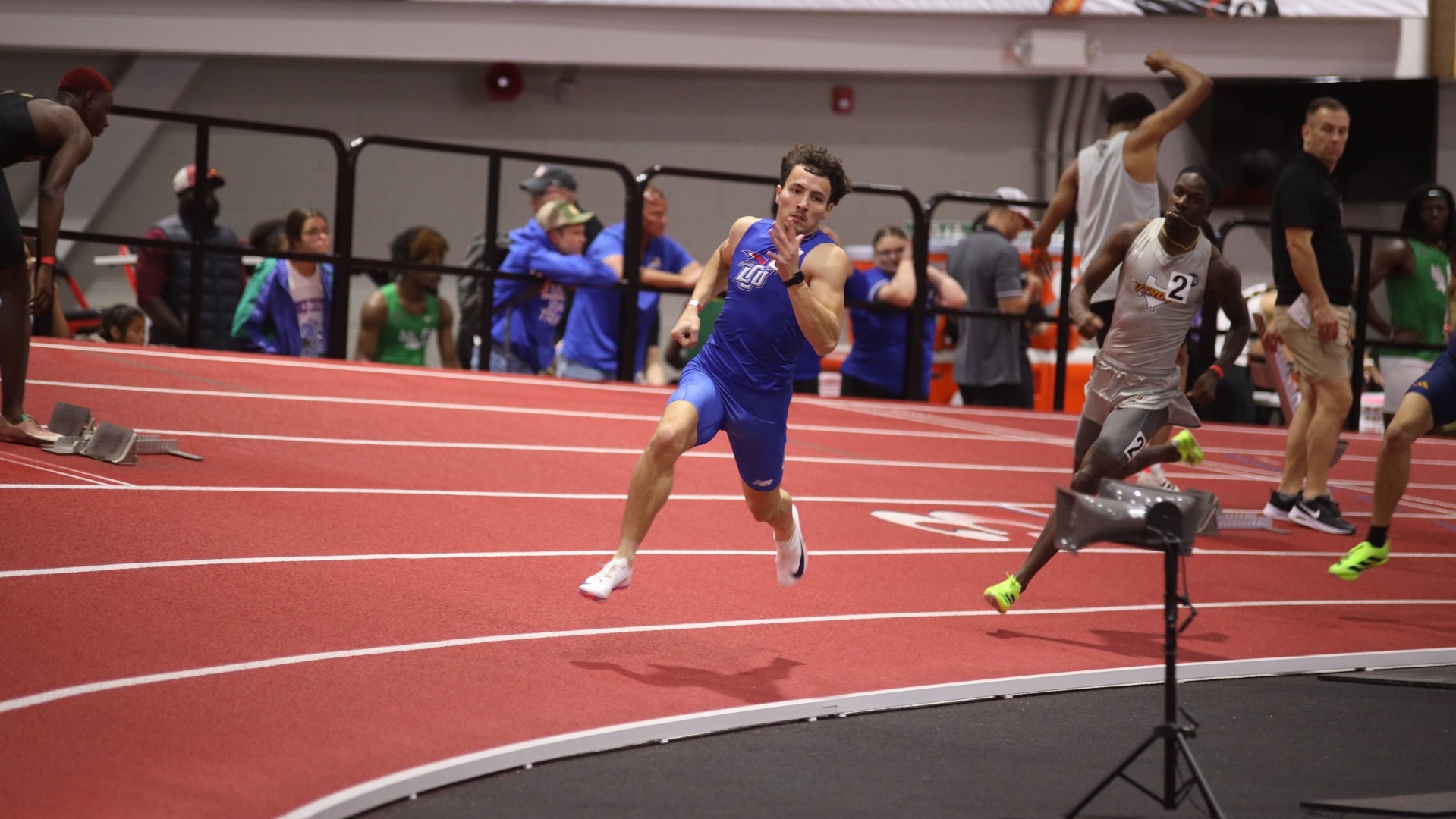 This is a photo of Lubbock Christian track athlete Daniel Sainez, wearing a blue uniform, running on a red track at Texas Tech. 