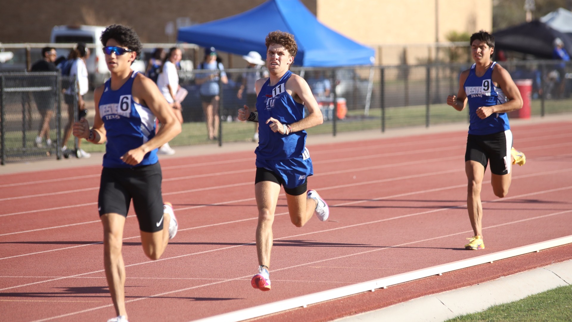 Lubbock Christain track athlete Gavin Morrison (blue uniform, #11) runs between a pair of Wester Texas College athletes during a meet at Texas Tech Univeristy. 