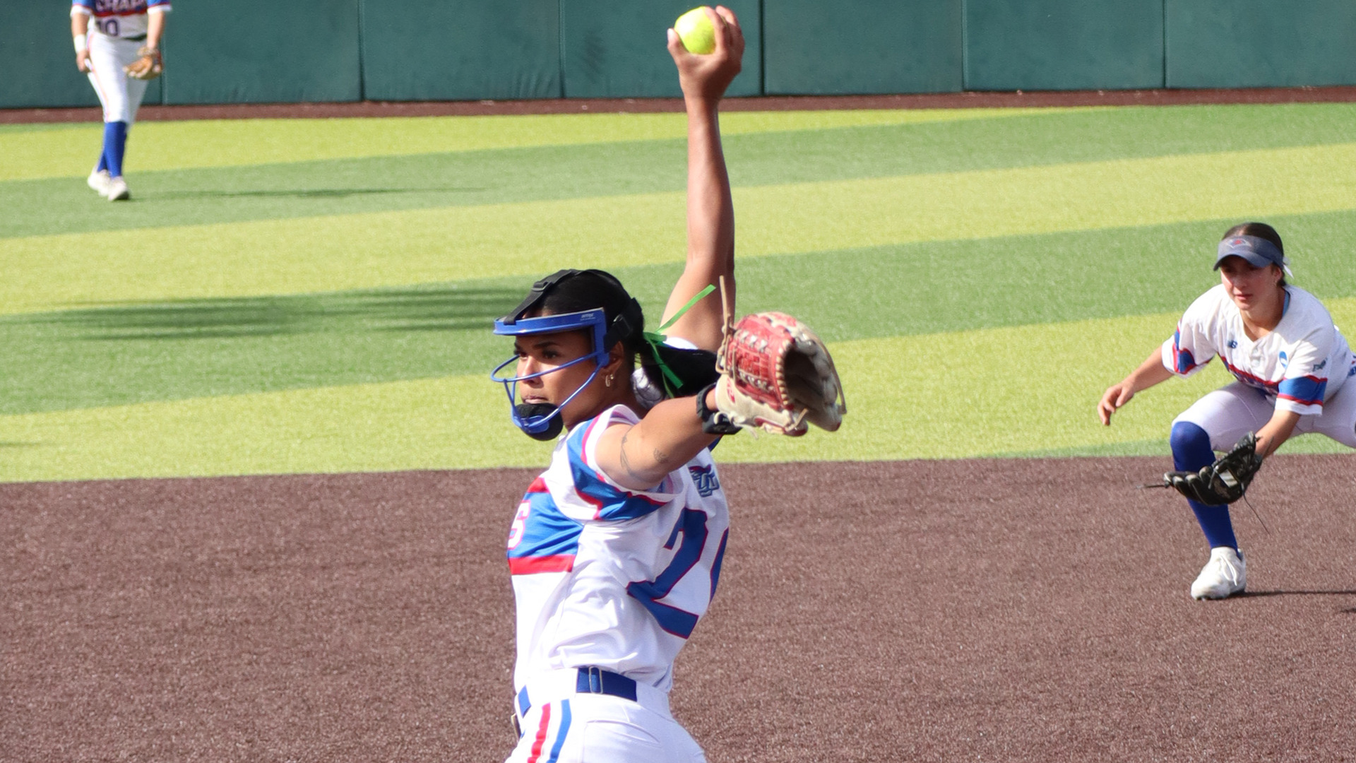 A Lubbock Christian University Lady Chaps softball pitcher wearing a white, blue, and red 
