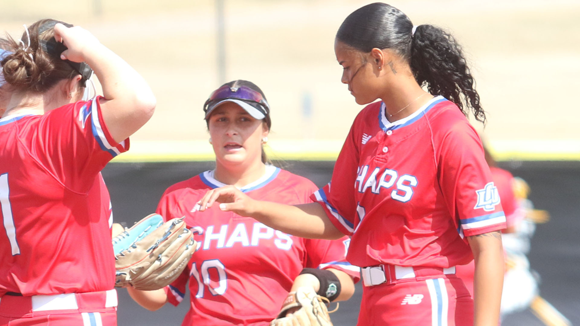 LCU softball players in red uniformas converge in a circle-visit