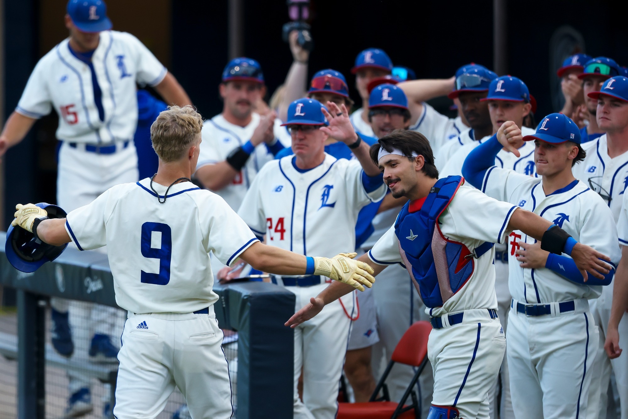 This is a photo of Lubbock Christian outfielder Hudson Grace (white jersey, #9) celebrating with teammates after hitting a home run.