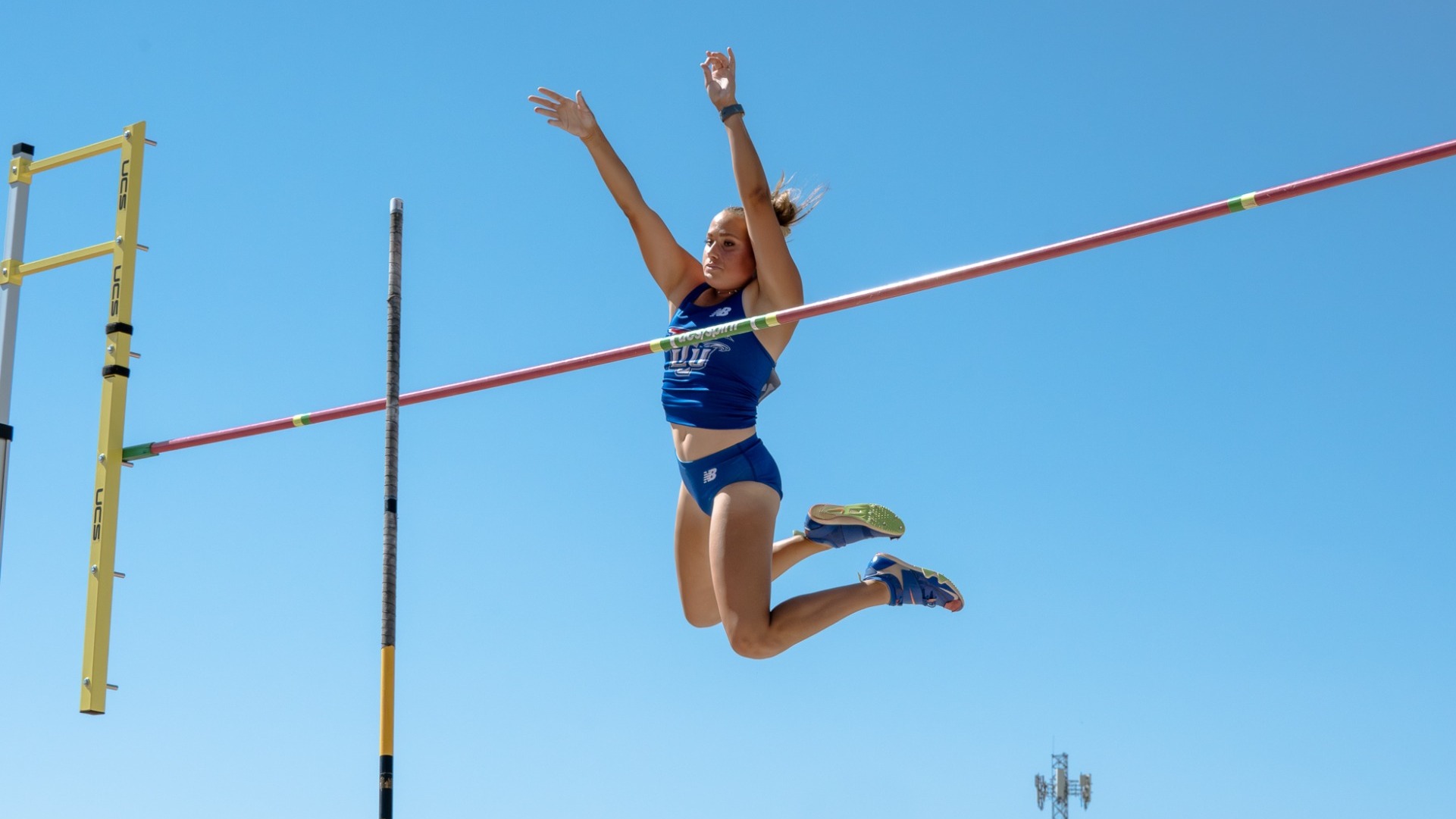 This is a photo of Lubbock Christian female athlete Drew Grellhesl (wearing a blue uniform) clearing the pole vault bar during the LSC Championship meet.