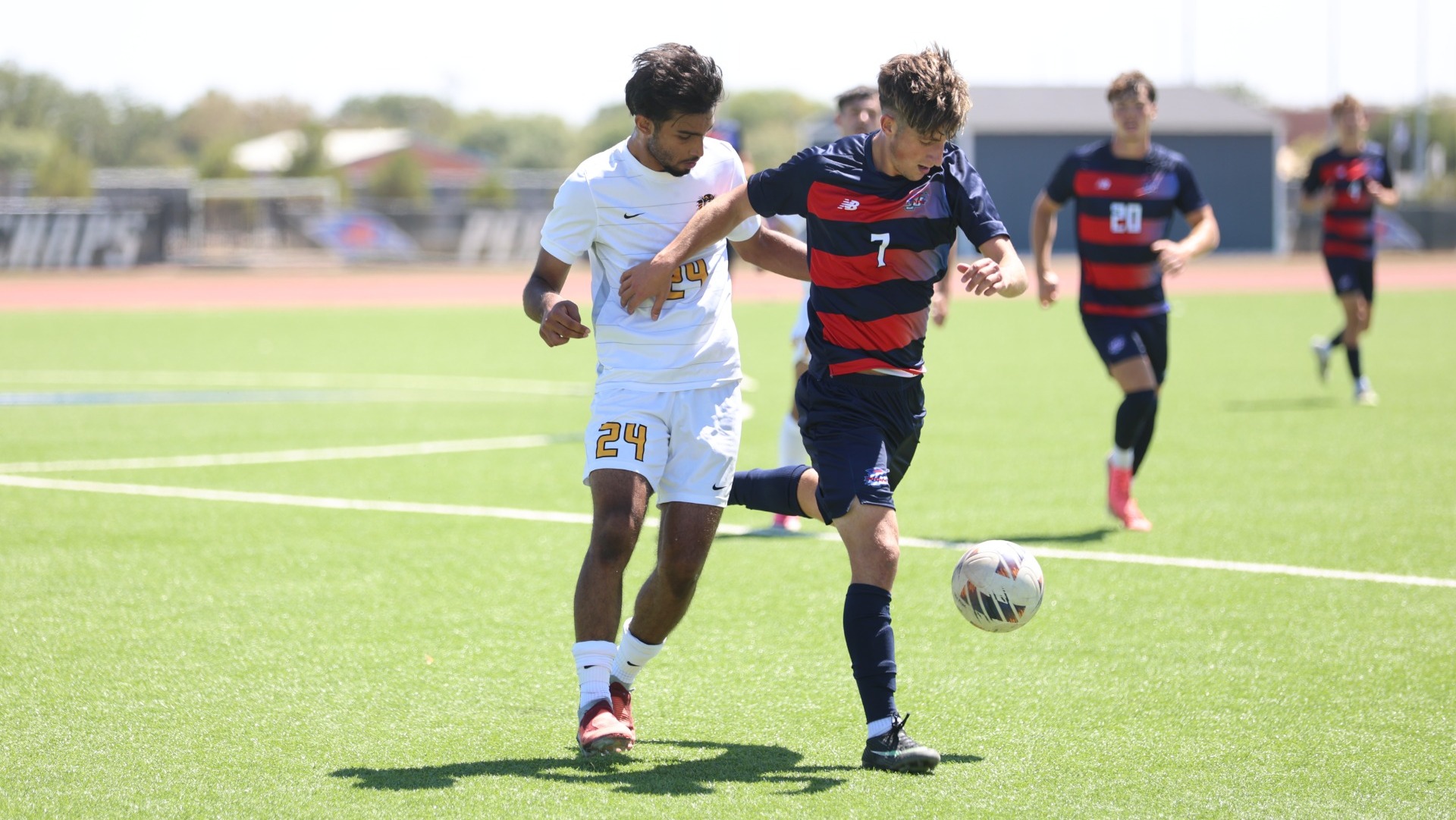 Lubbock Christian forward Alex Lachevre (blue jersey, #7) holds of a Fort Hays State defender (white jersey) during a game at the LCU Soccer & Track Complex. 