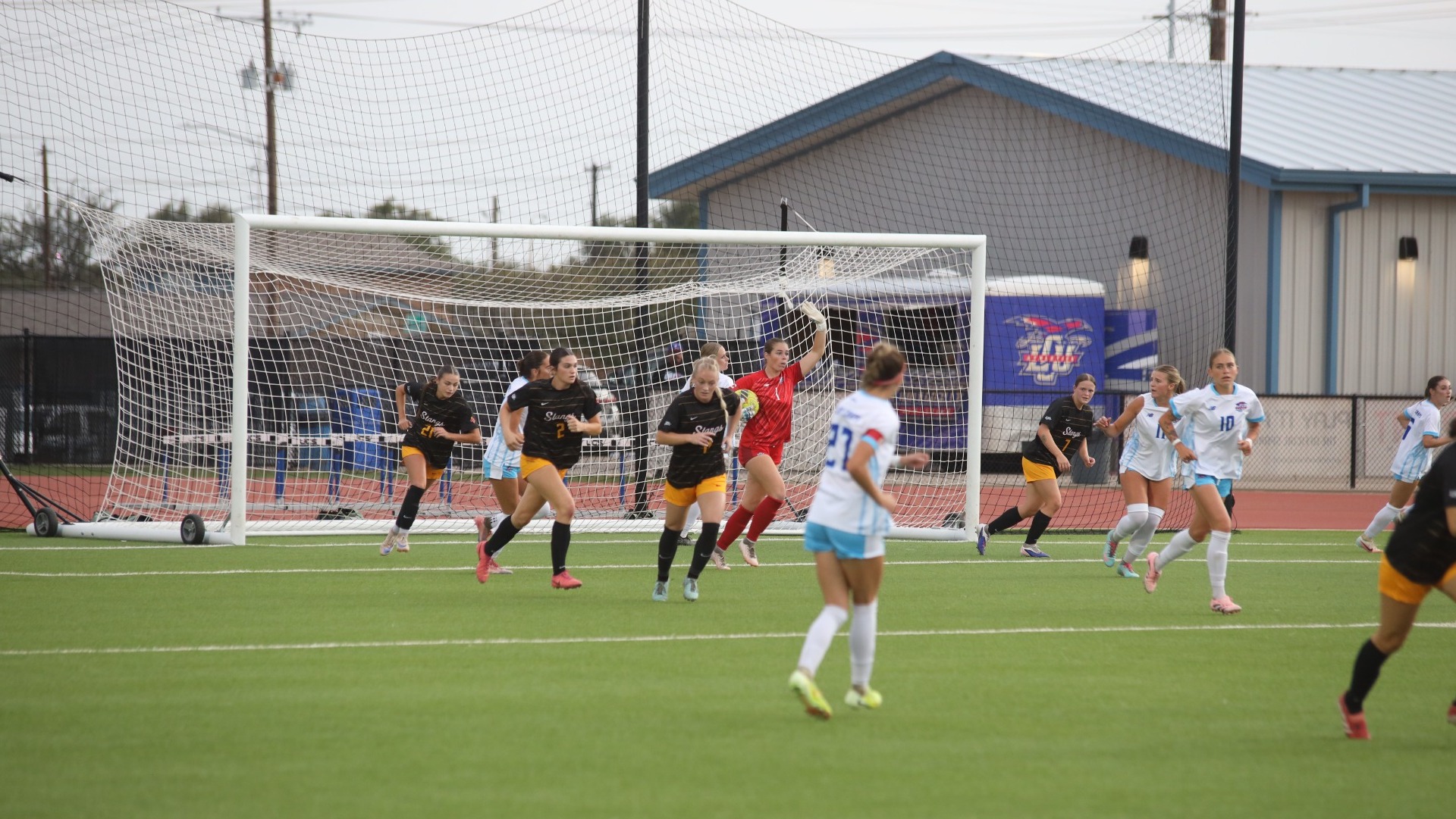 This is a photo of goalkeeper Emma Wright (red jersey, #1) yelling instructions to her teammates and carrying the soccer ball during a game at the LCU Soccer & Track Complex.