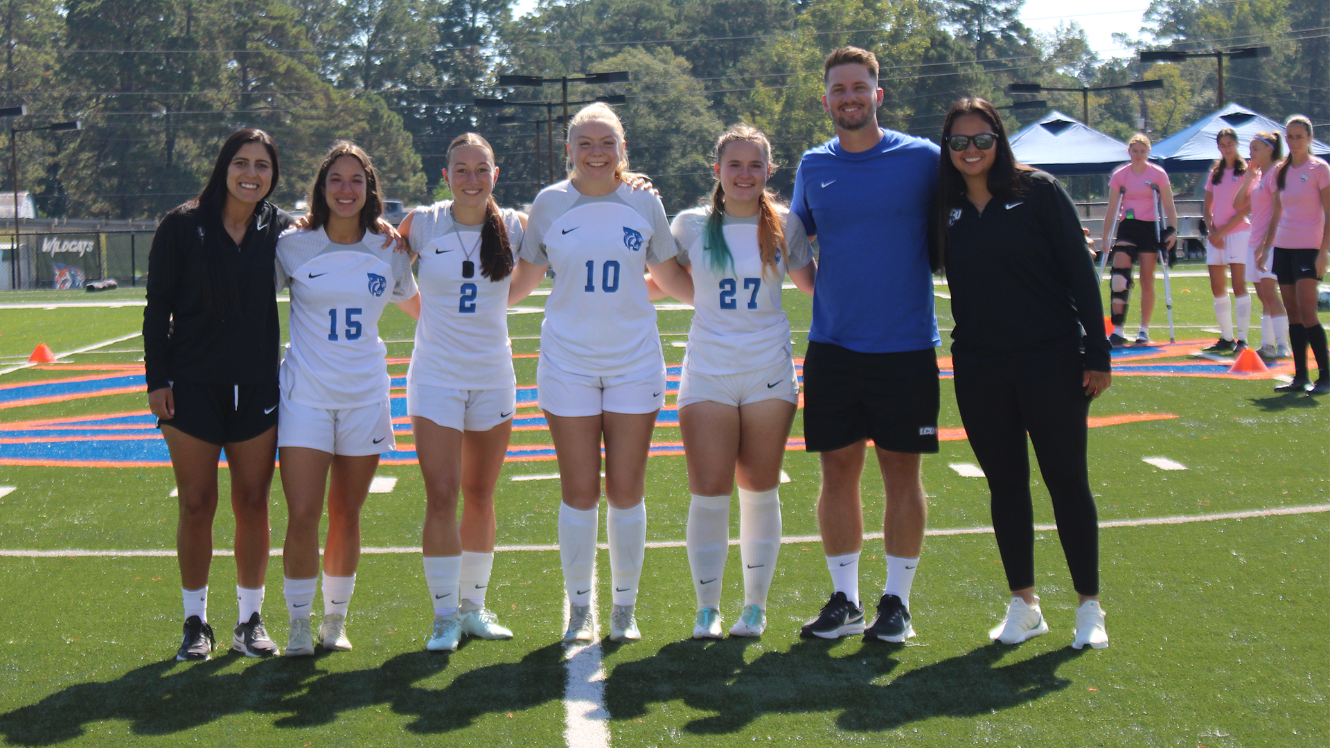 Seniors Tanika Rother, Emma Hicklin, Ana Guedes, & Isabella Andrews with Harrison Houle & coaching staff during senior day ceremony