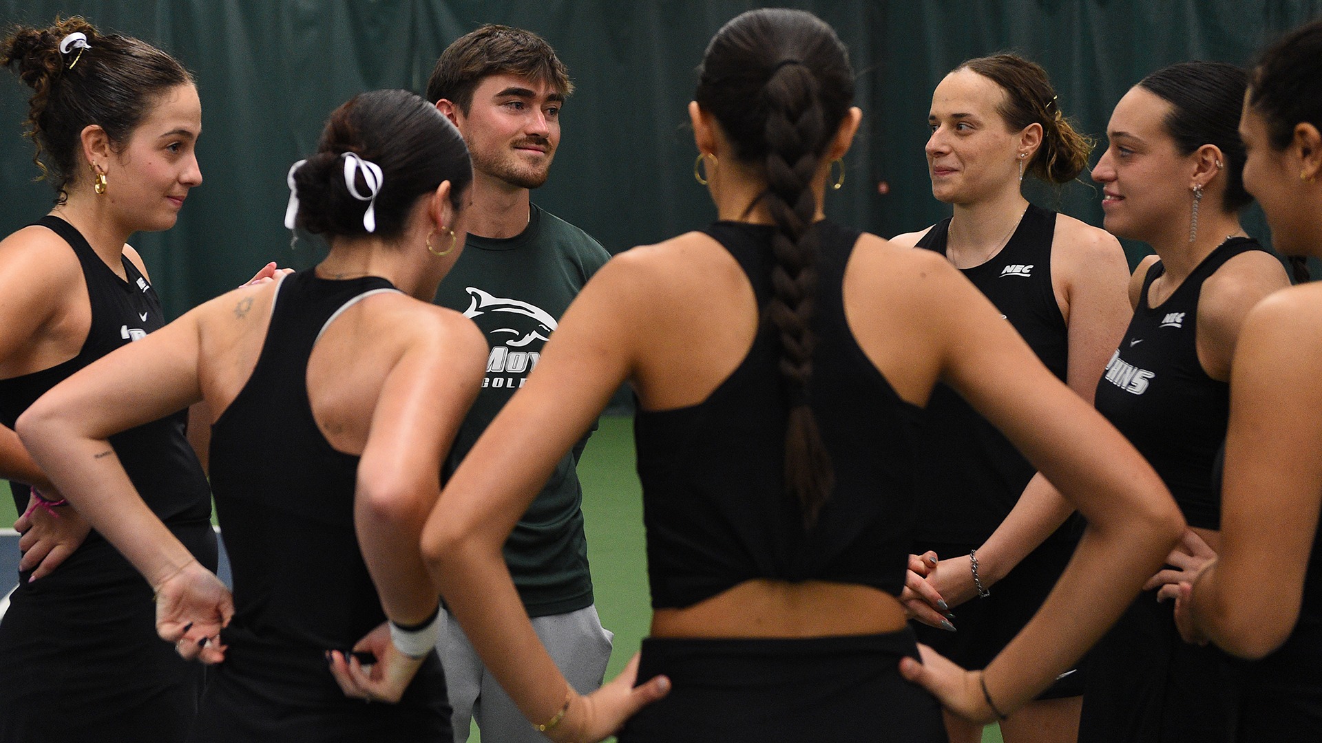 Le Moyne College women's tennis team huddles around assistant coach Peter Hatton