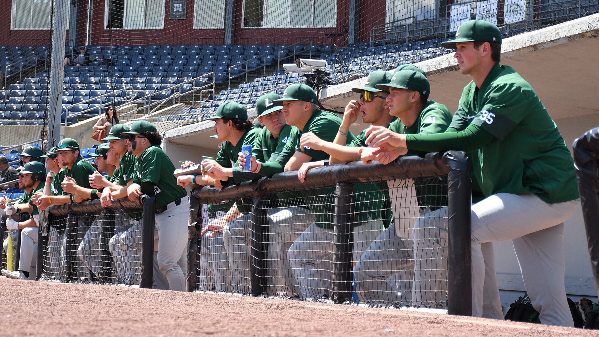 Members of the baseball team watch from the dugout against Wagner at the NEC Championship