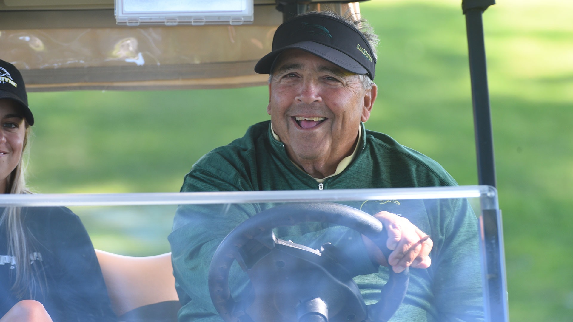 Joe Tesori smiles for the camera from a golf cart during Le Moyne's match against Niagara