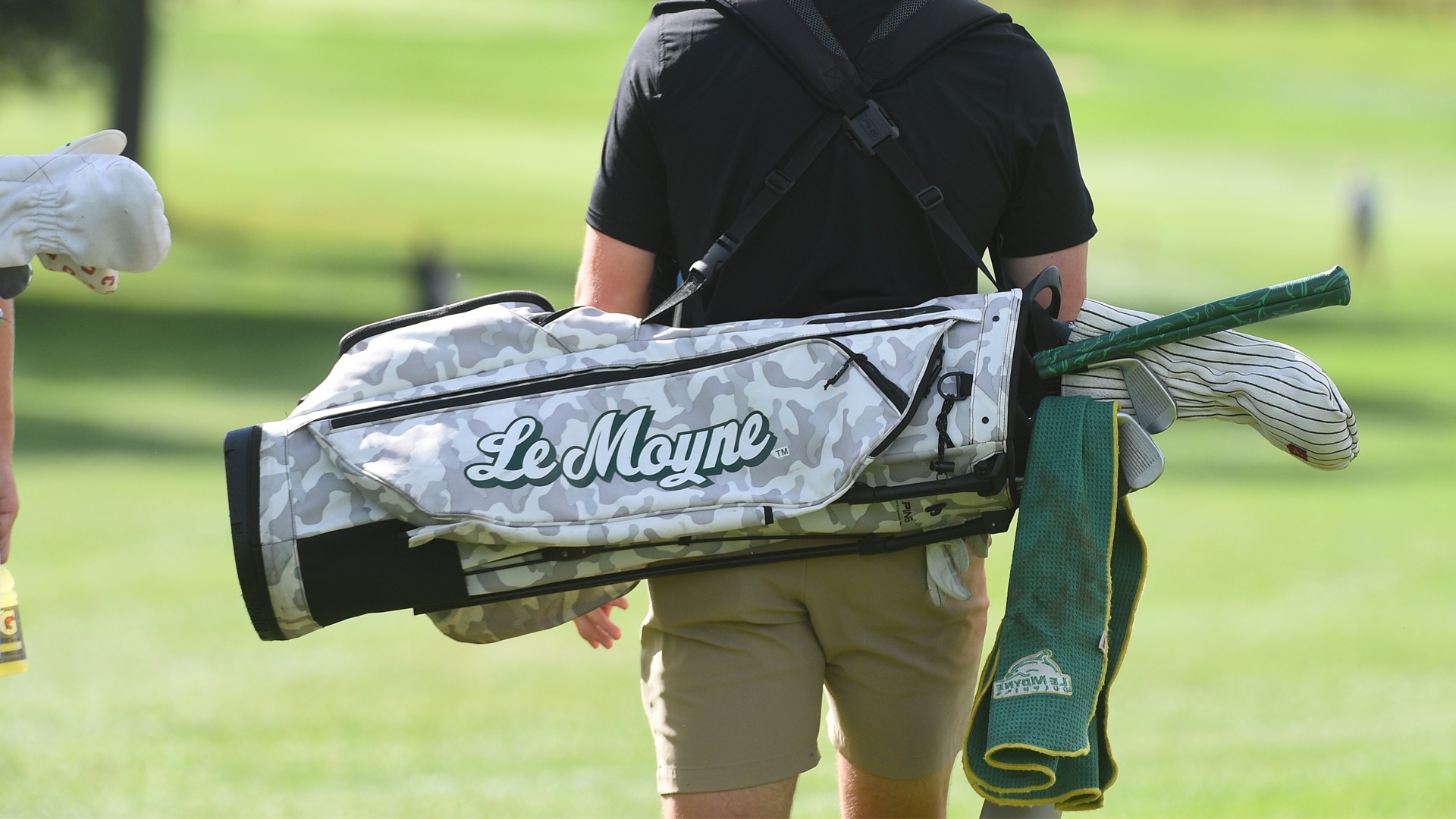 A golfer carries their bag down the fairway