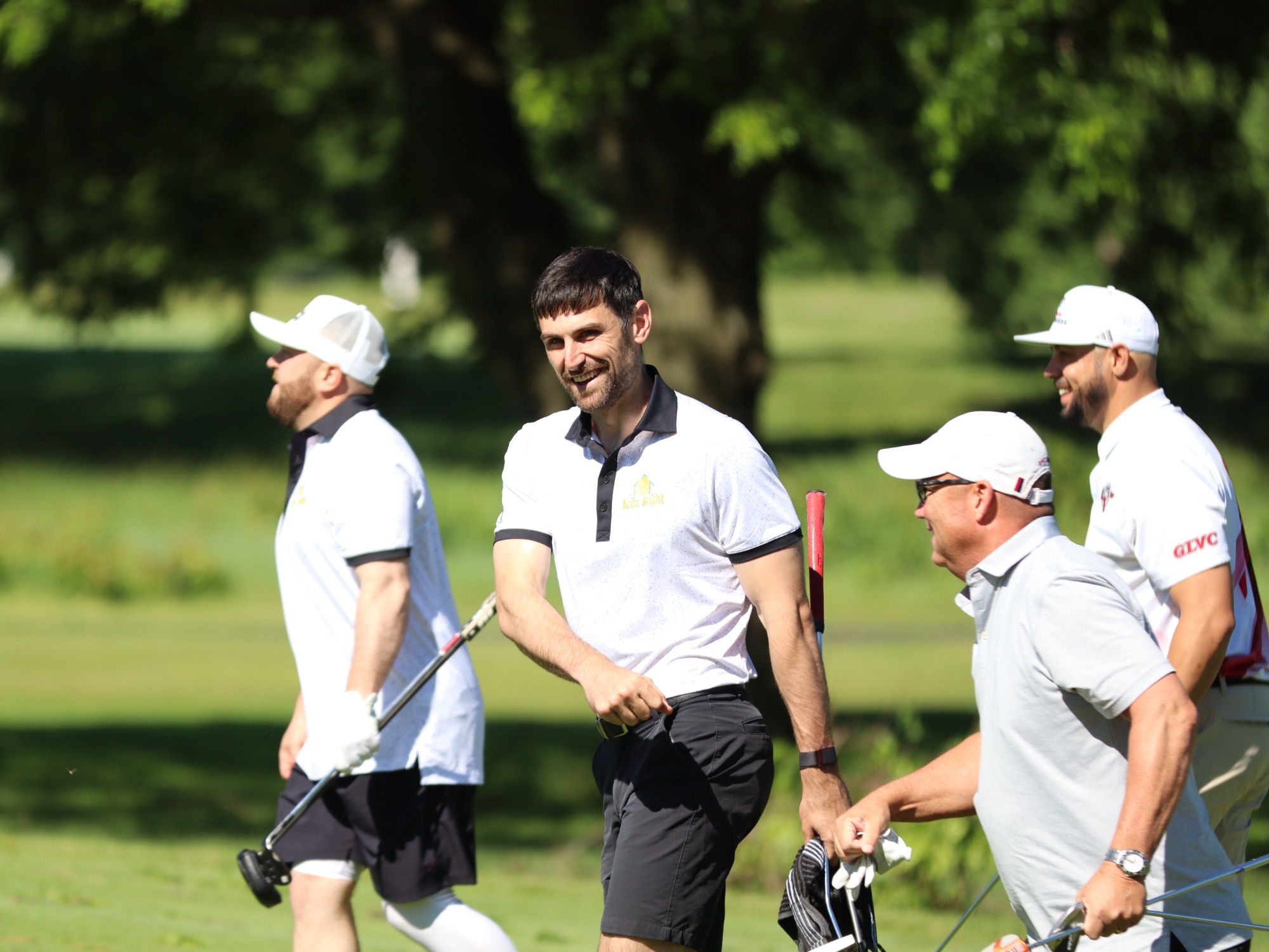 members of a golf group smile walking off the course