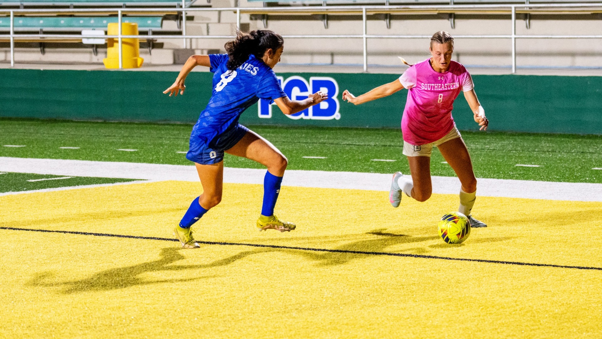 Women's soccer player Brooke Opferman on the attack vs HCU defender, taking a shot around the net