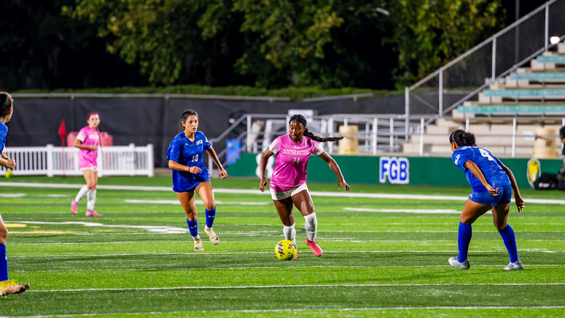 Women's soccer player Aja Nelson on the attack against HCU defenders in Strawberry Stadium