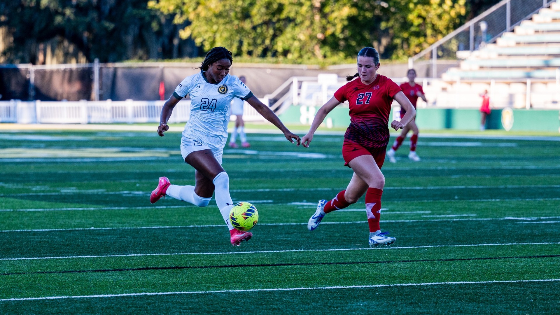 Women's soccer player Aja Nelson vs Nicholls defender launching a shot around the net