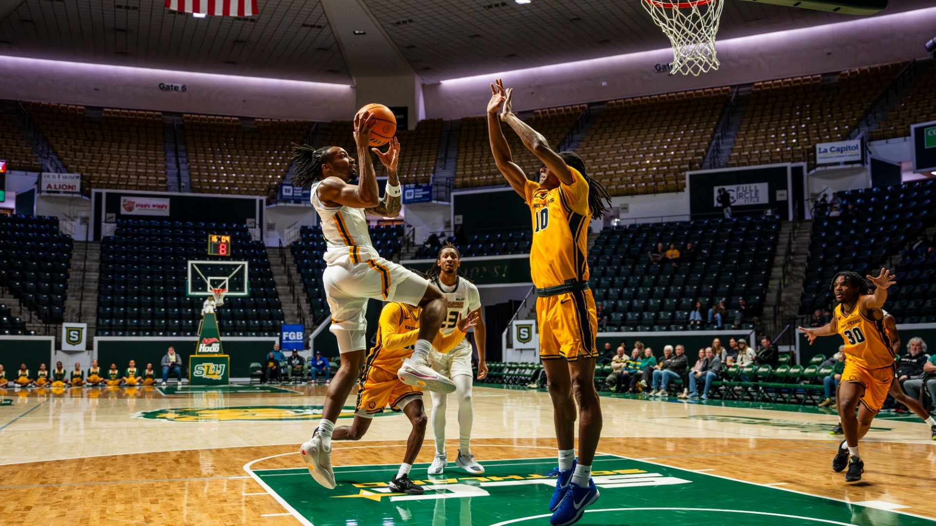 Ethan Pickett driving baseline and attempting a jump shoot through contact over East Texas A&M defenders