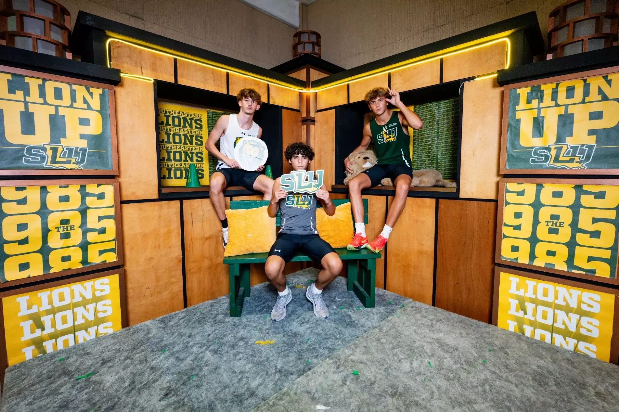 Matthew Berthlot, Hunter Eslick, and Peyton Dufrene take a picture in front of a promo backdrop