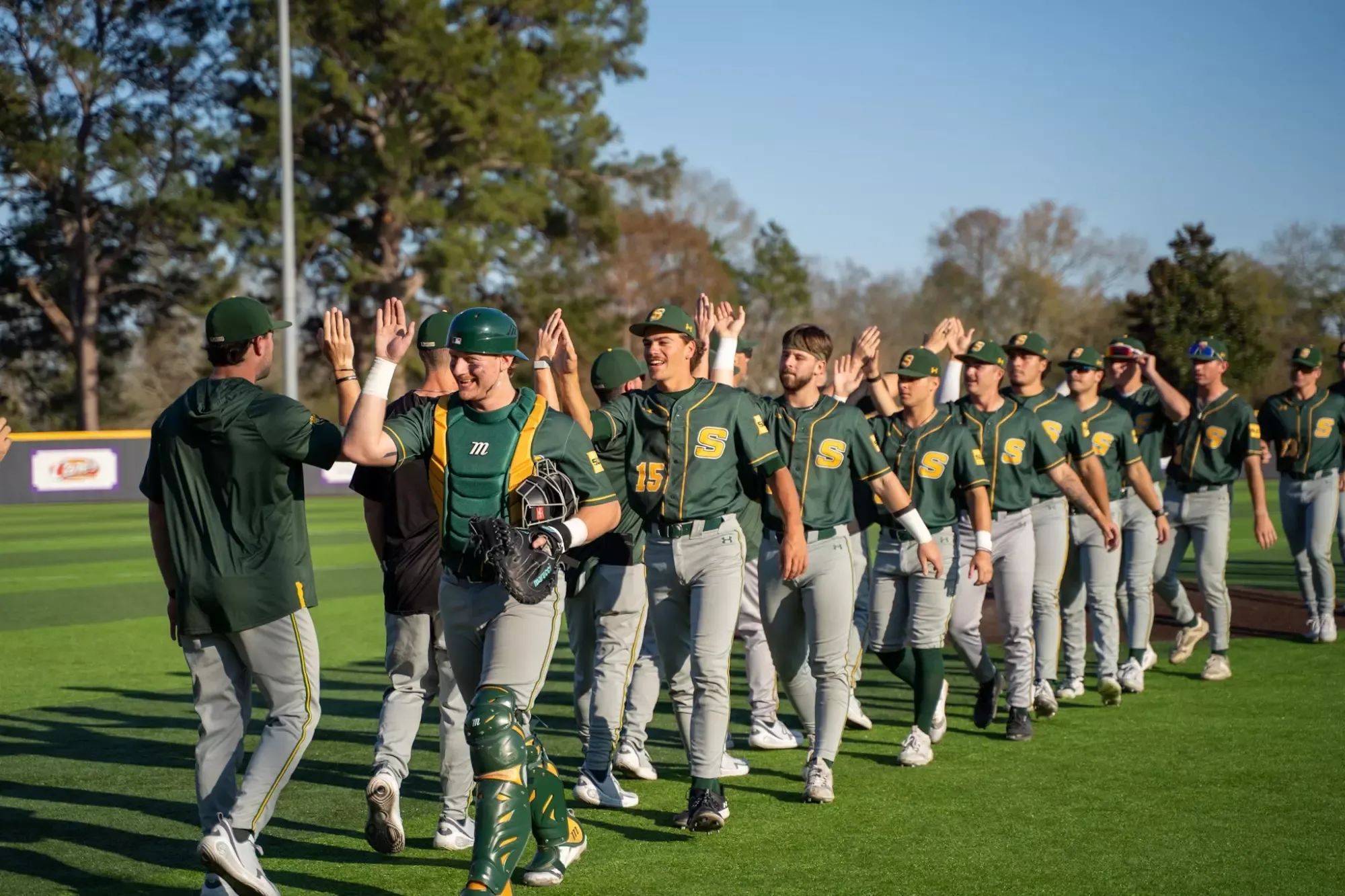 The SLU baseball team offers up hi-fives to their teammates.