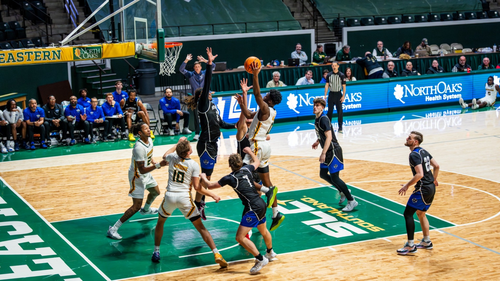 Jeremy Elyzee elevating to finish around the rim over multiple UNO defenders