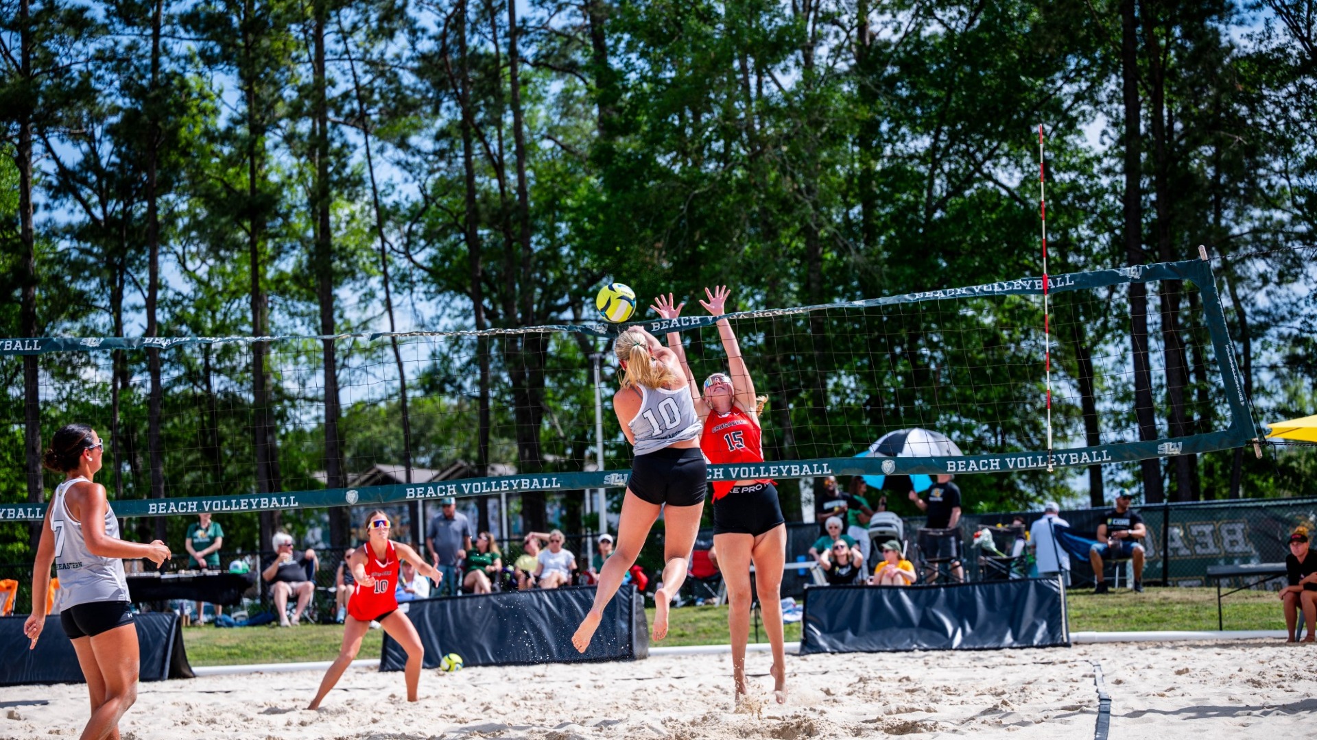 Taylor Stockwell spiking the ball over the net alongside pair partner Ally Alfonso vs William Carey defender