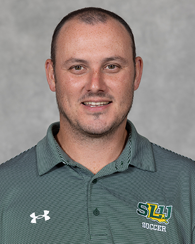 2026 Southeastern head coach Nathan Gillespie headshot in green SLU polo, smiling at the camera