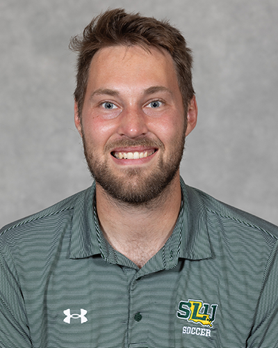 2026 Southeastern assistant coach Willem Kelson headshot in green SLU polo, smiling at the camera