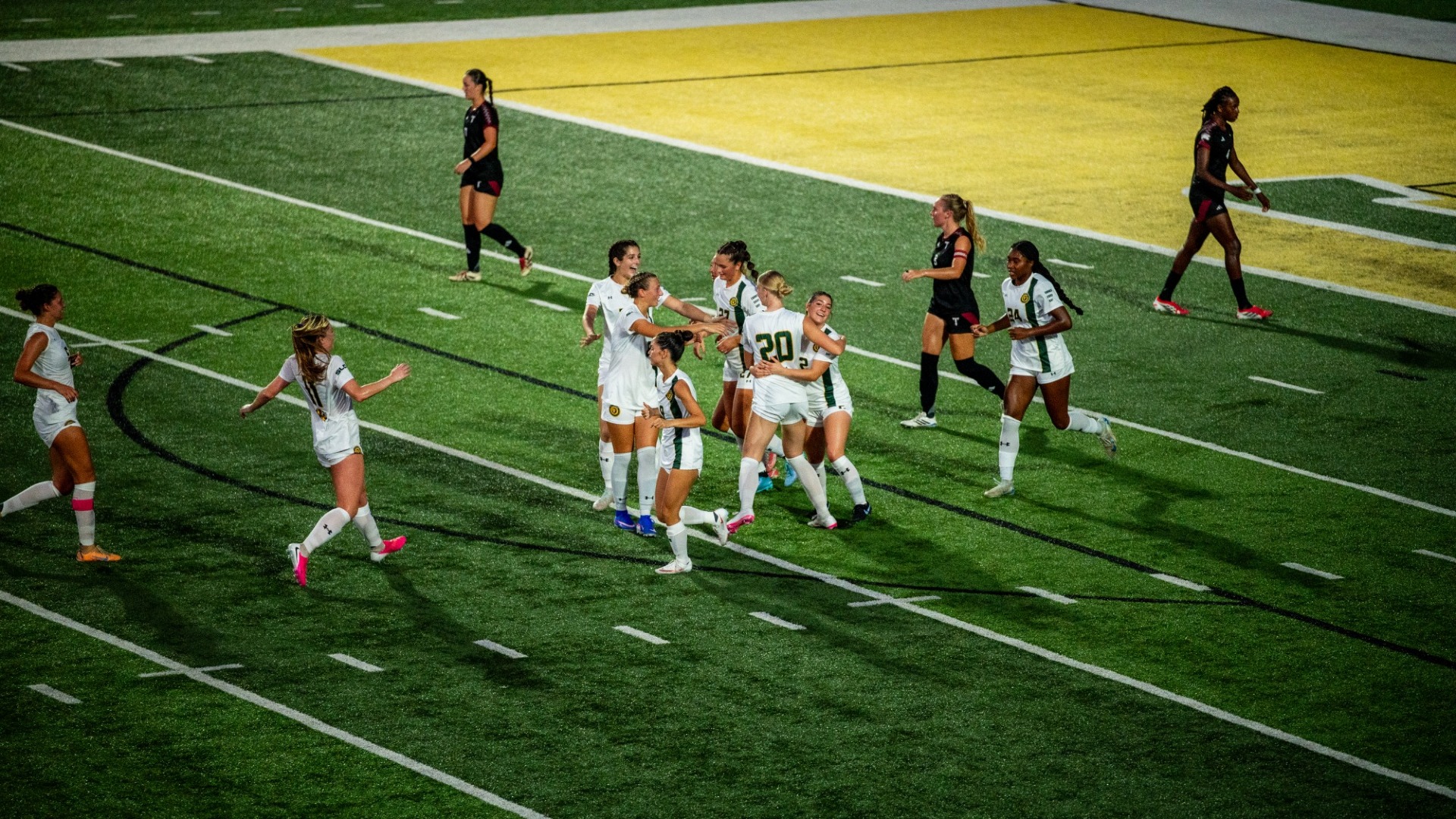 Women's soccer player Ella Quinlan celebrating with multiple teammates after scoring a goal vs Troy