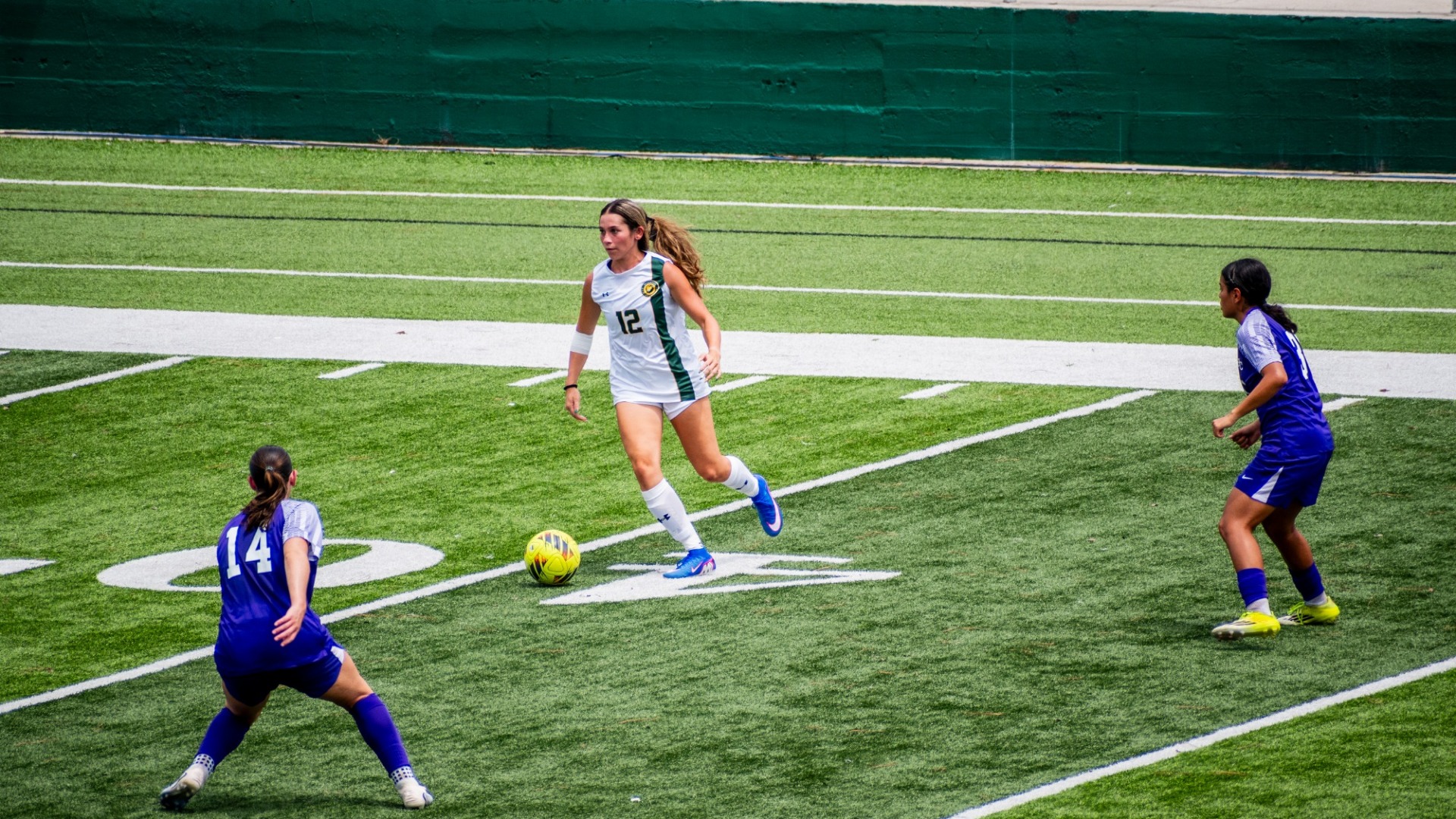 Women's soccer player Loegan Alia working with the ball to block off Spring Hill defenders 