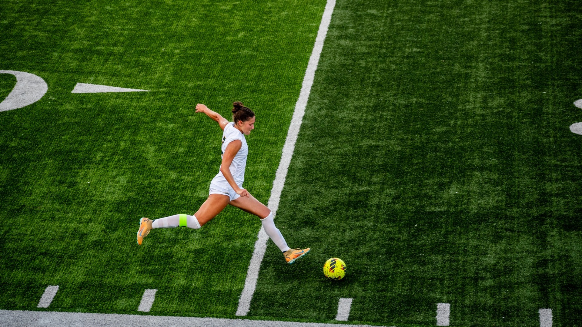 Isabella Walls kicking the ball up the field in Strawberry Stadium vs West Florida defenders 