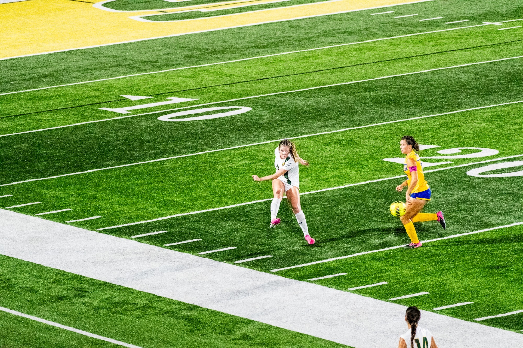 Lainey Connell launching the ball up the field vs McNeese defender looking to block the pass 