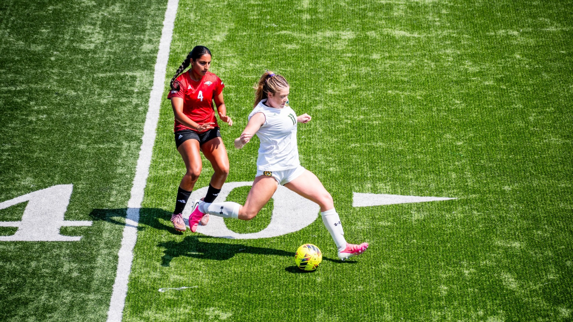 Lainey Connell kicking the ball up the field for an offensive attack vs UIW defender