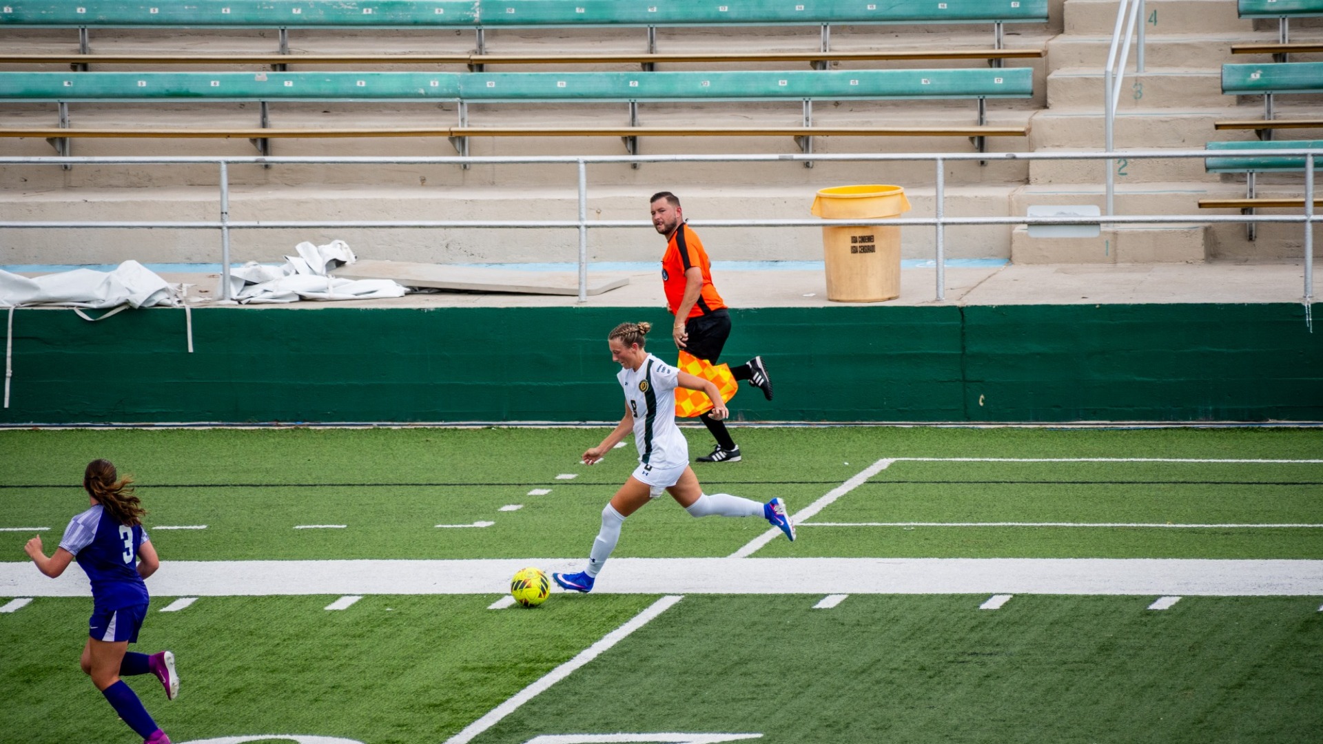 Women's soccer player Brooke Opferman (white jersey) pushing the ball up the field vs Spring Hill defenders at Strawberry Stadium