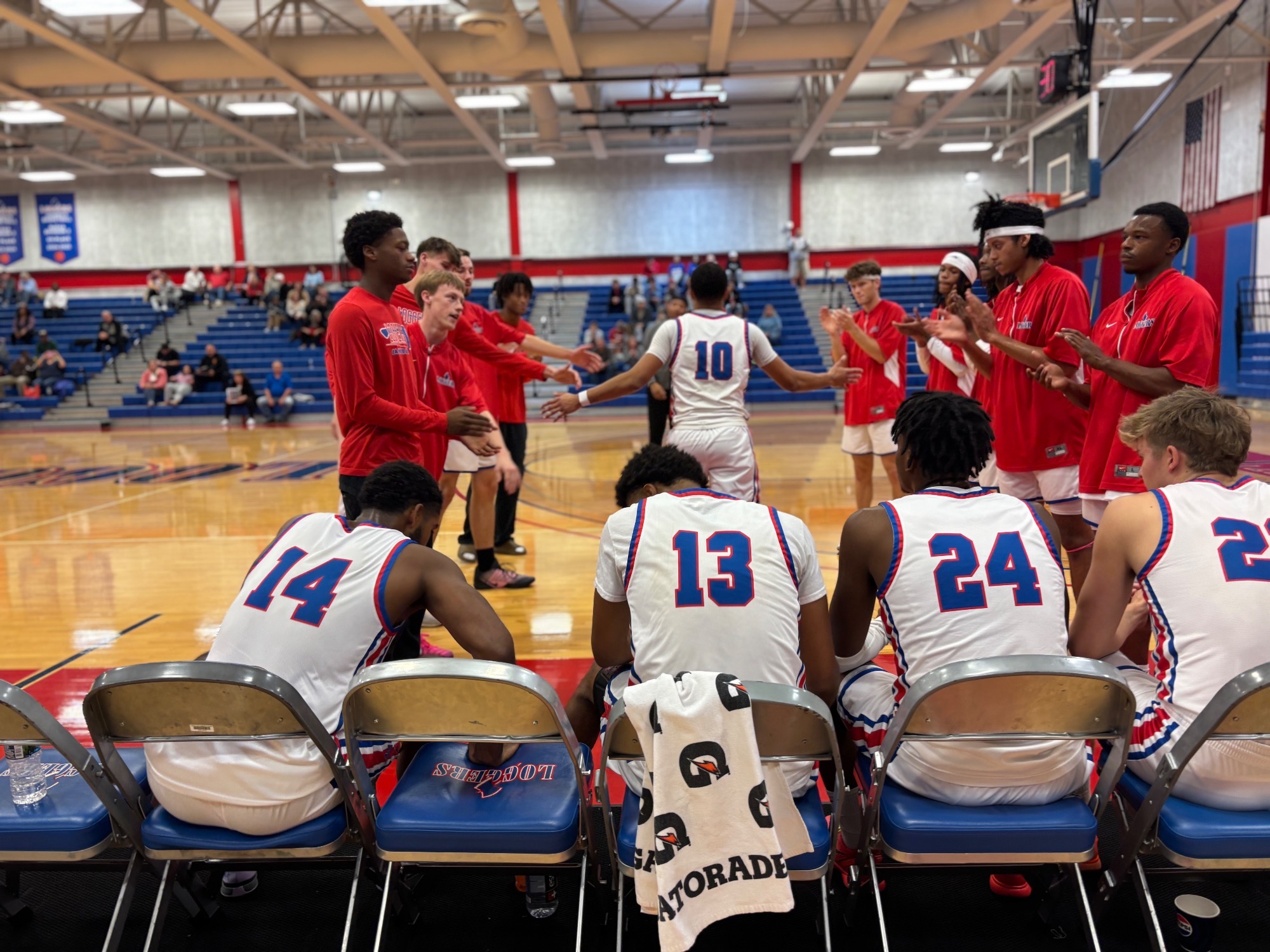 LLCC men's basketball team sitting on chairs.