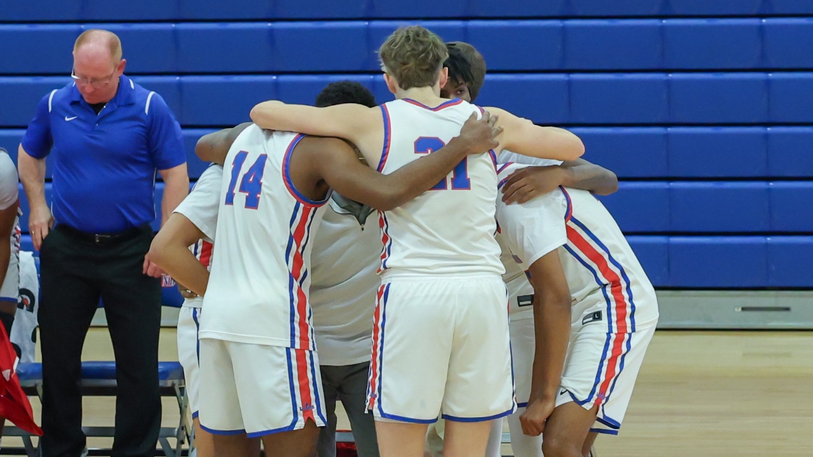 LLCC men's basketball players standing in a circle.