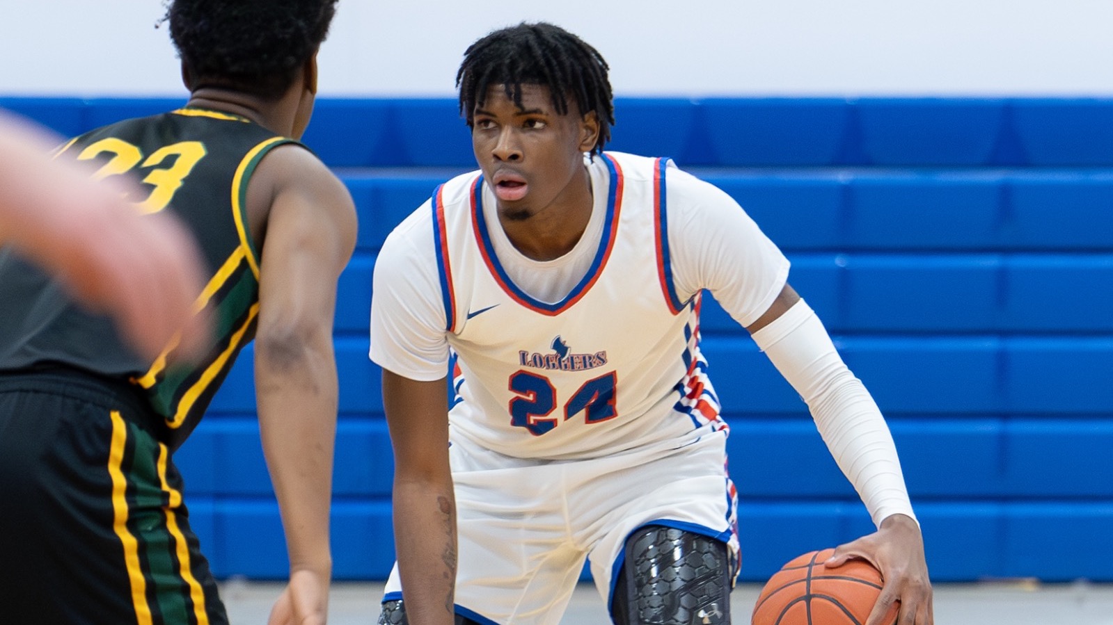 LLCC men's basketball player dribbling.