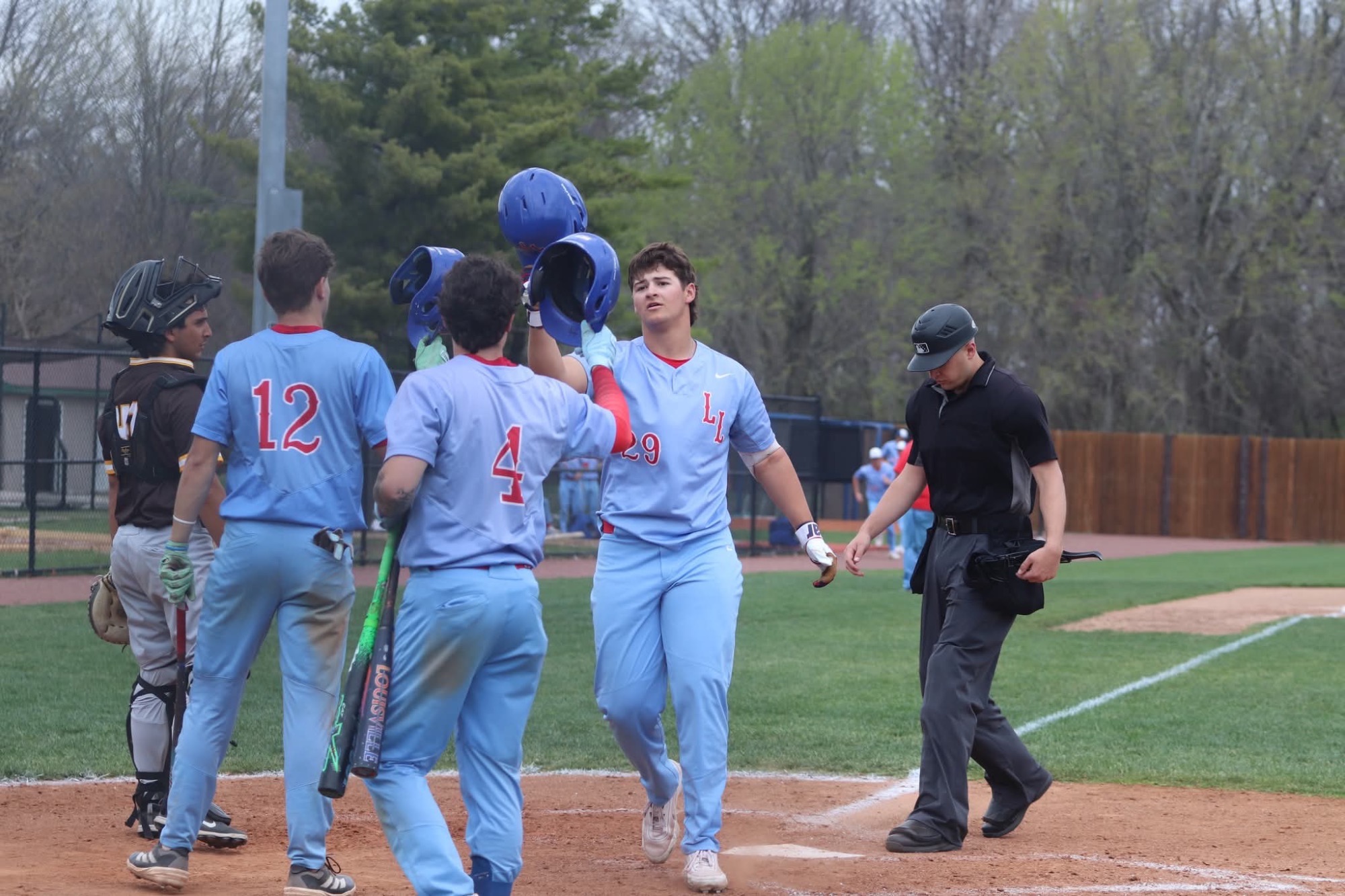 LLCC baseball players hitting helmets.