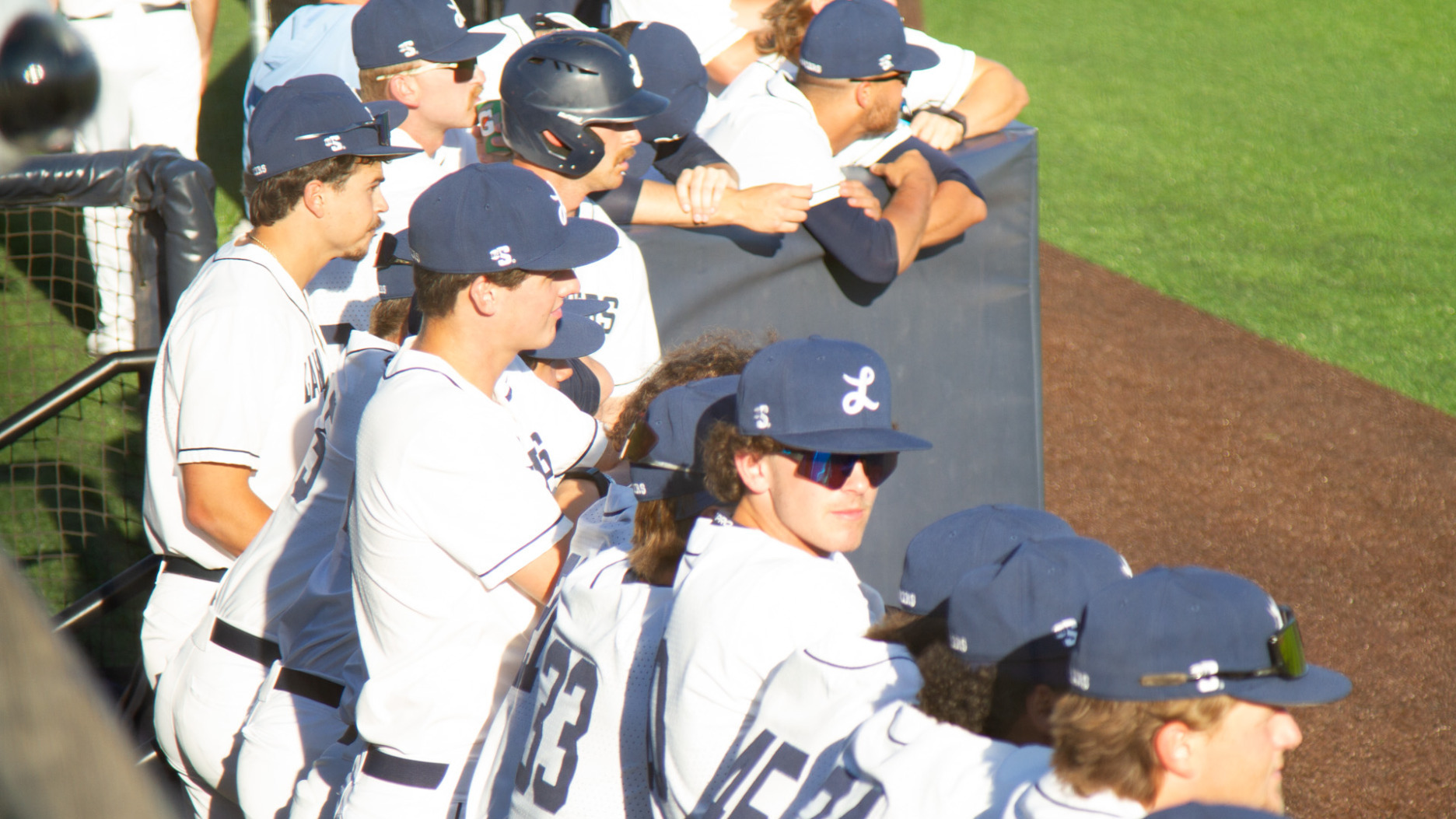 Players in the Longwood dugout look out at the field