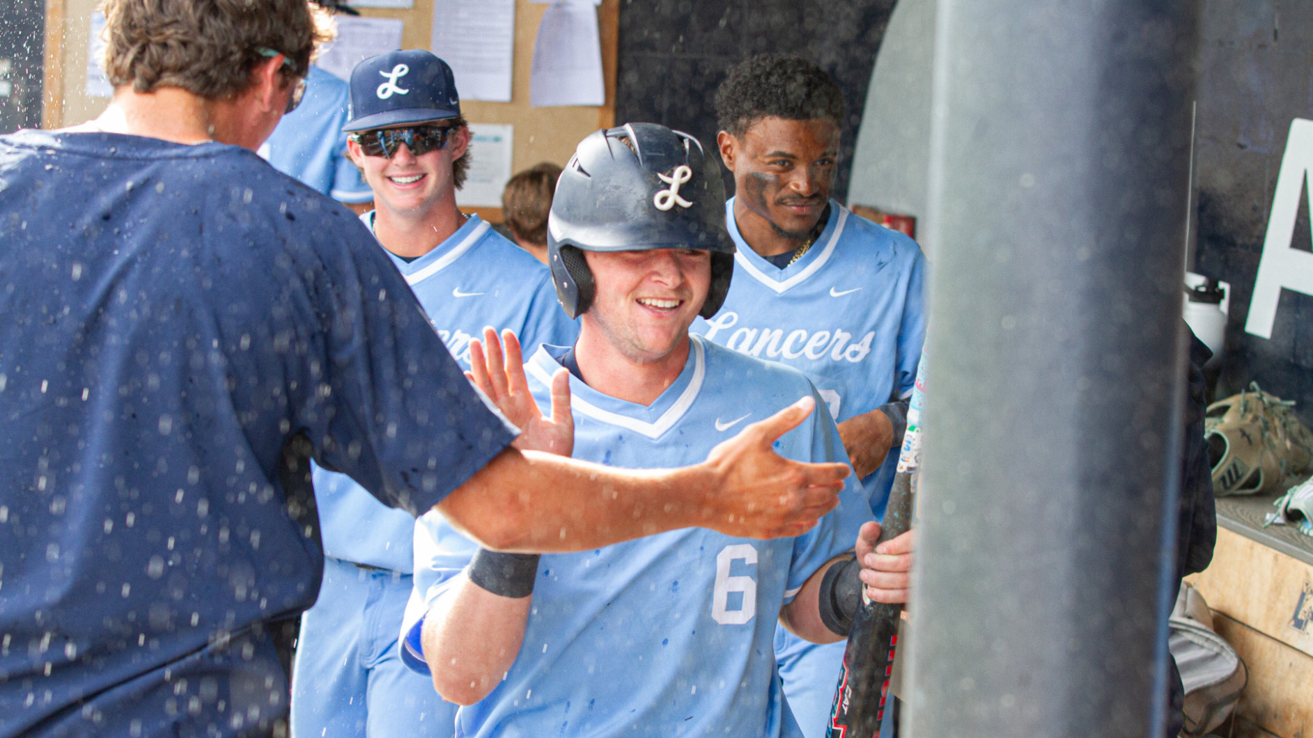 Jack McMullan high fives teammates in the dugout