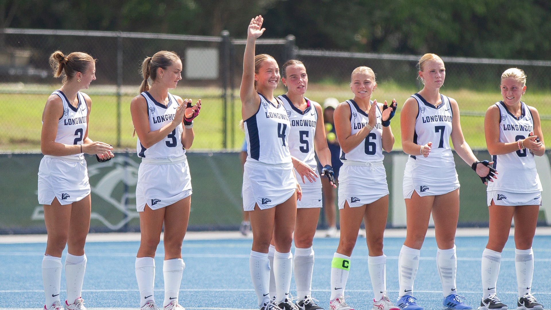 Freshman Sawyer Anderson waves to the crowd with her teammates clapping after being announced during the starting lineup introductions prior to the Lancers home contest vs. Queens. 