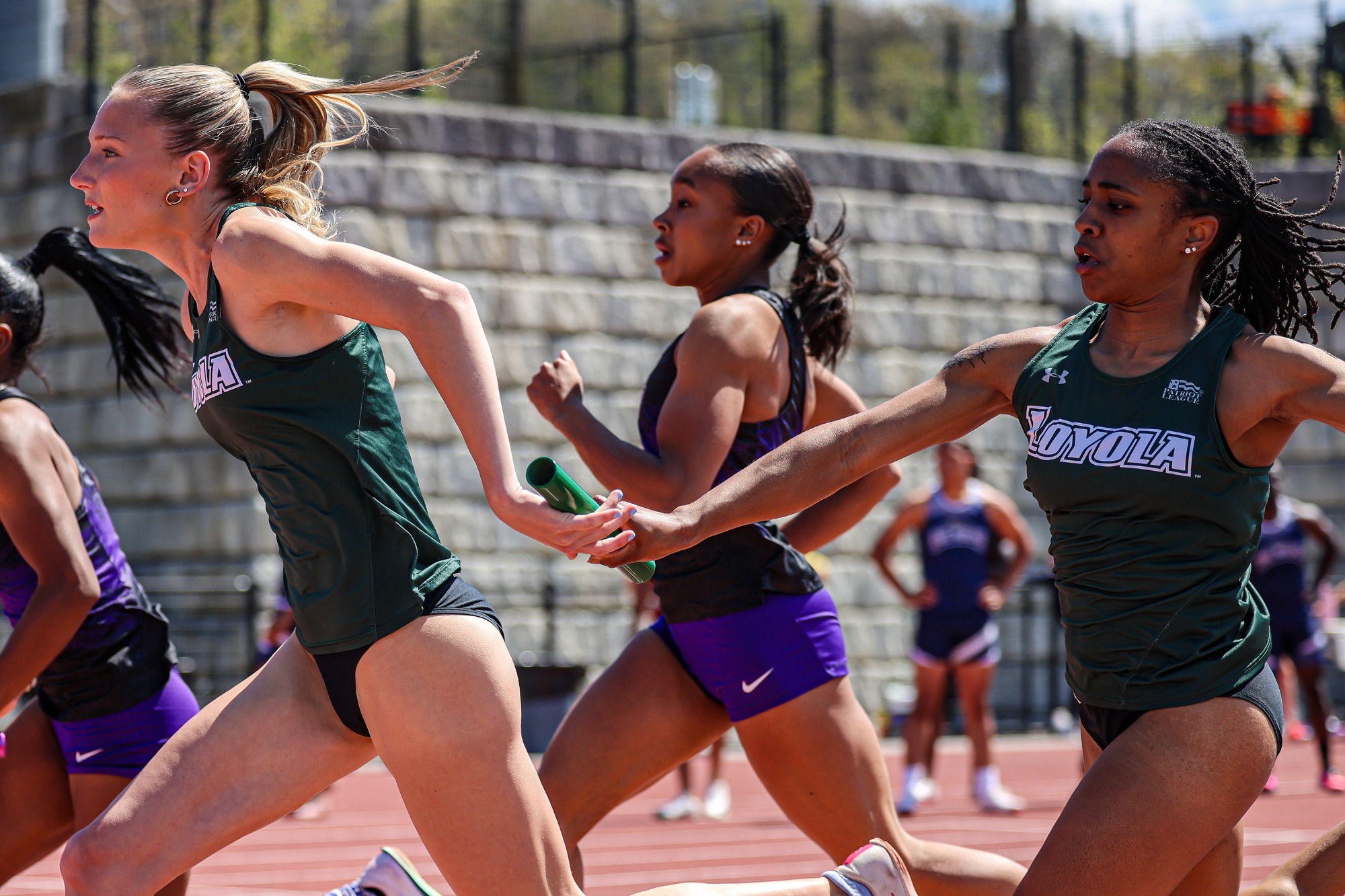 Maddie Van Haren receives a baton from Lauryn Clarke