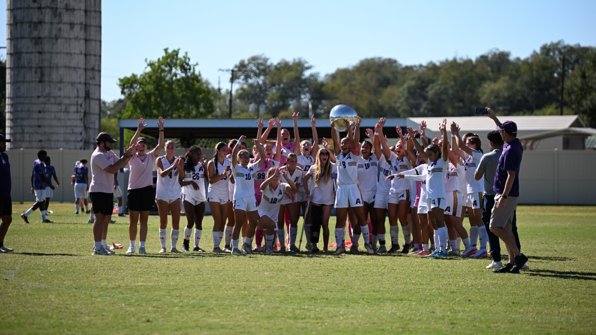 Women's Soccer Team celebrates their Red River Rivalry win as Nelly Dallmann lifts the Cup