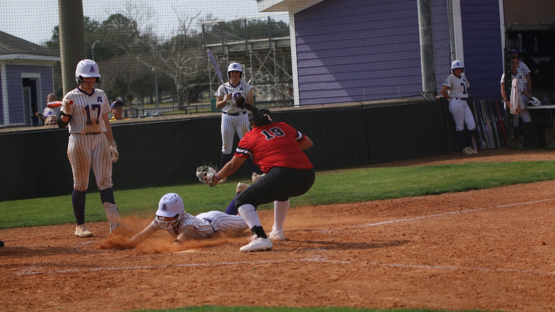 An LSUA player slides headfirst into home after a passed ball