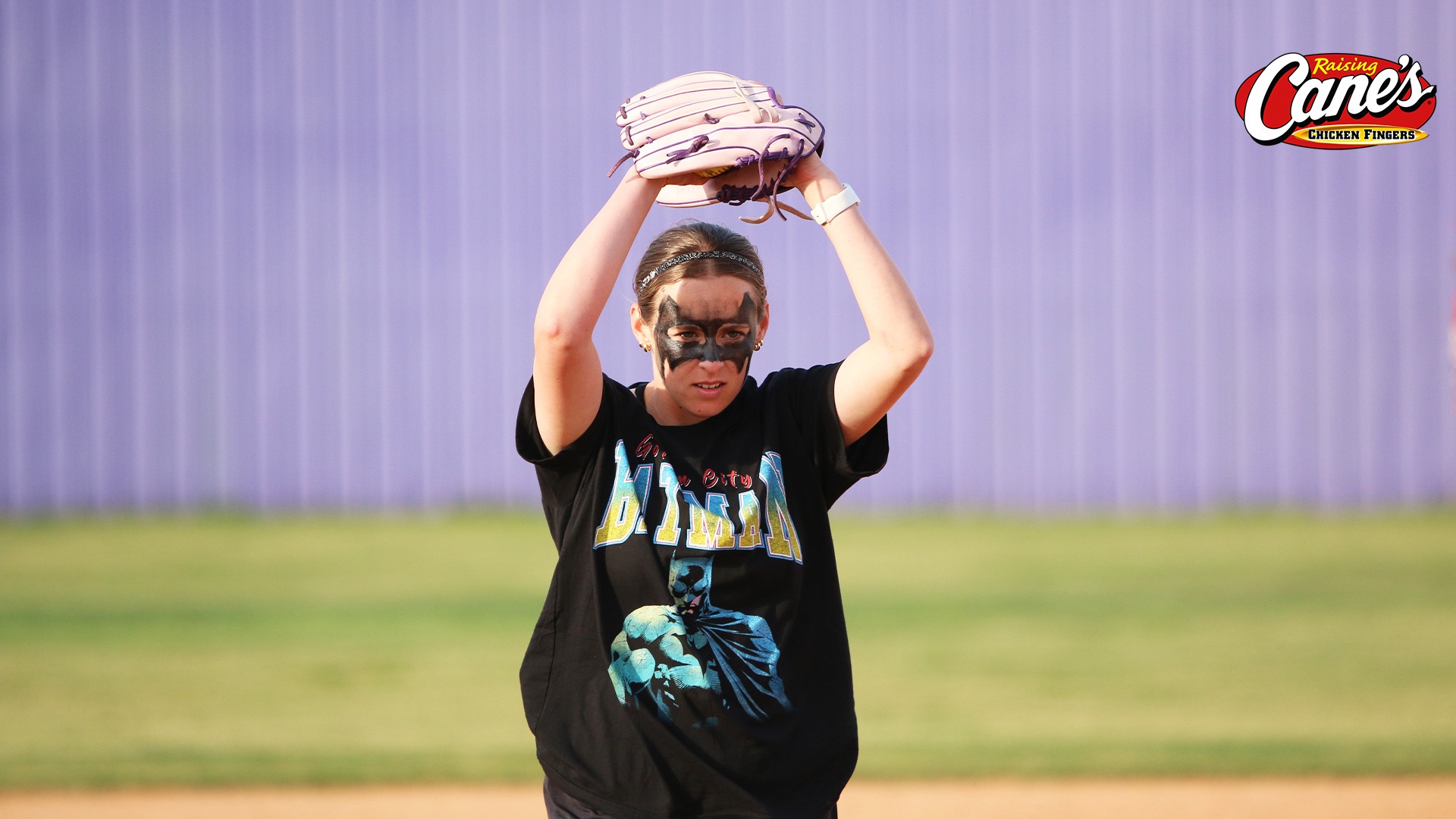 Alyssa Boutte delivers a pitch during a costume practice (dressed in a Bat Man t-shirt with Bat Man eye makeup)