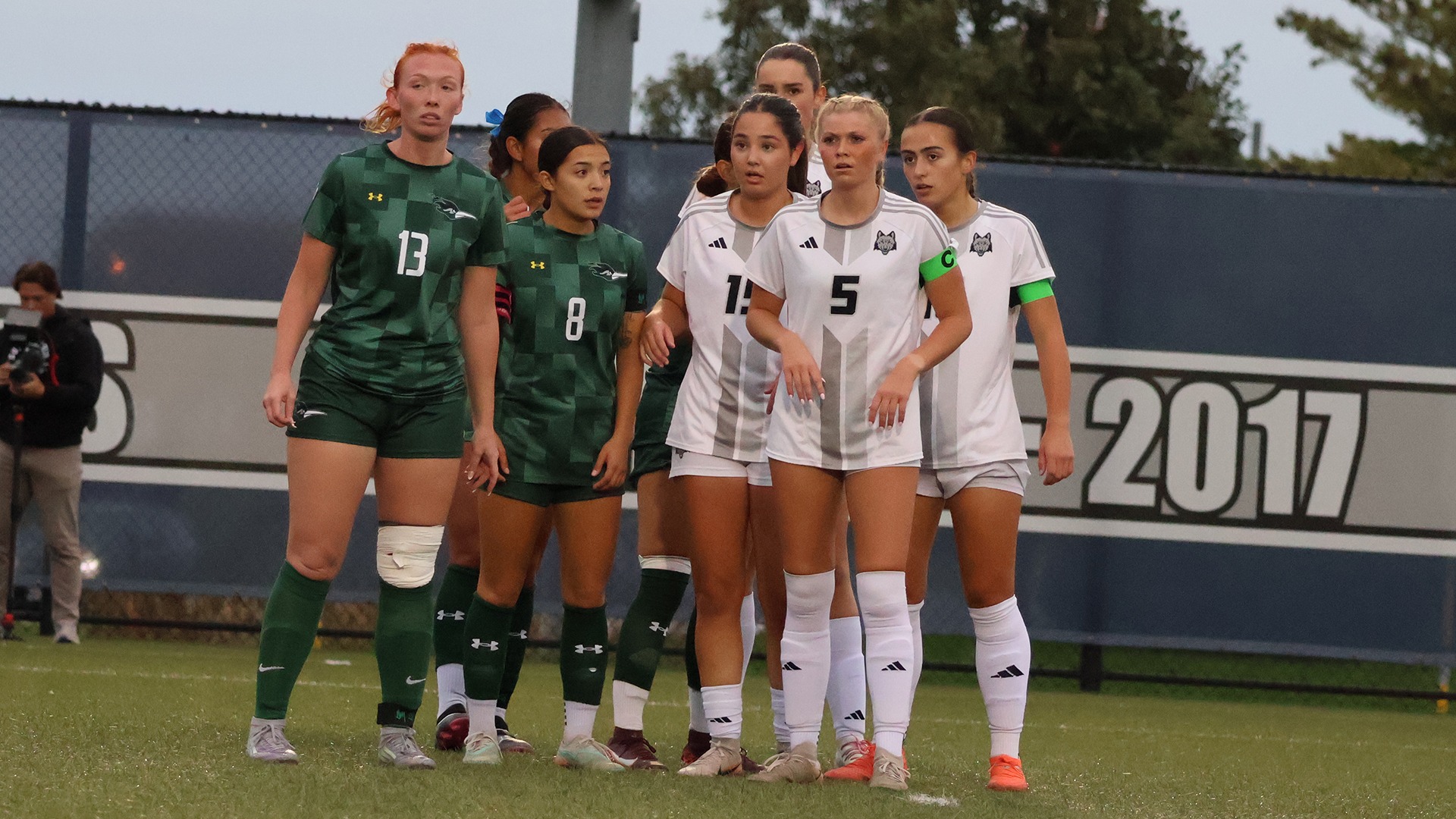Women's soccer players Hayleigh Motelet, Fay den Hoed, Maddie Marquette, and Roos Zwolschen line up for a corner kick.