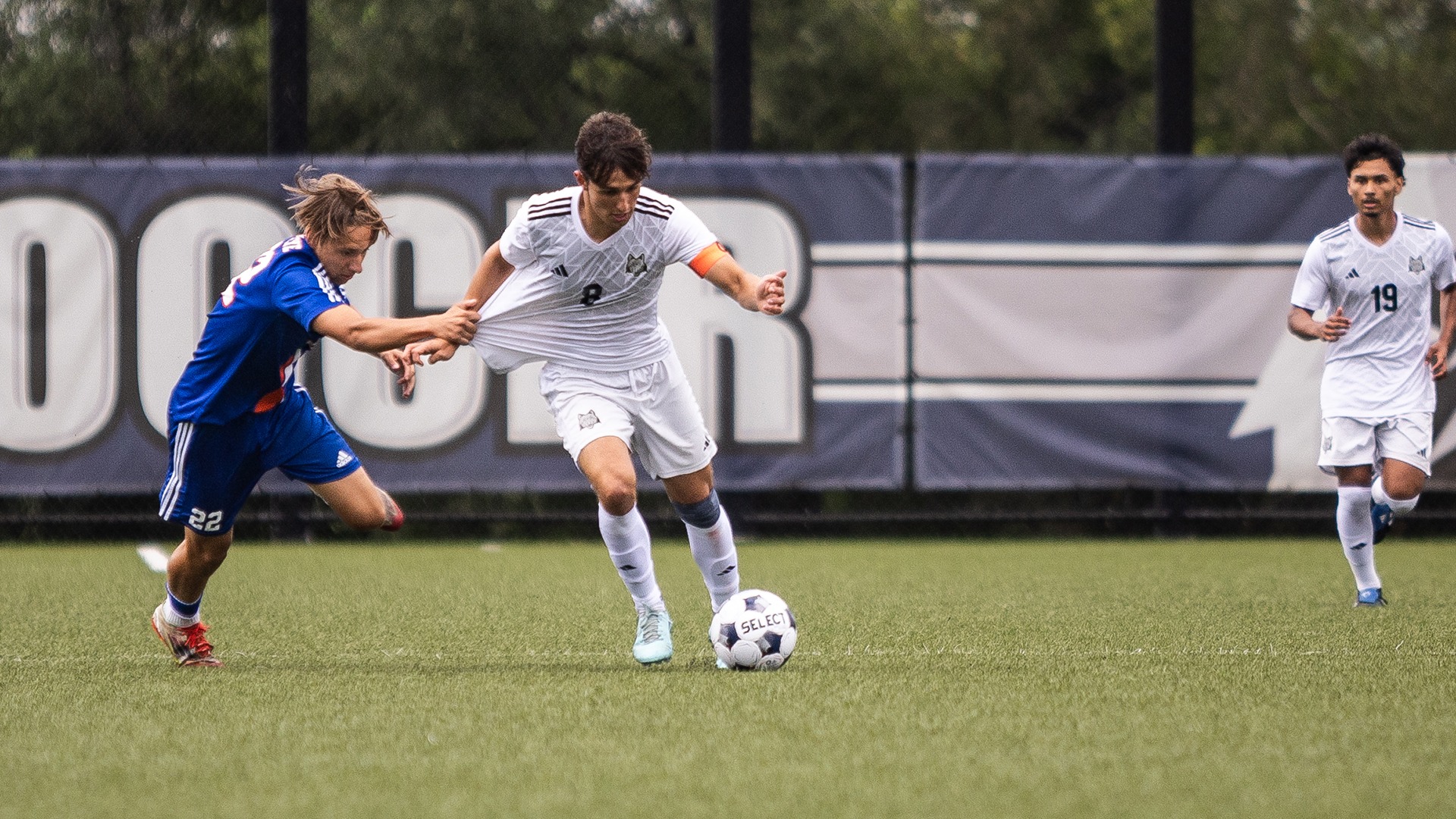 Gui Amaral holds off an opposing player as he dribbles the ball up the pitch.