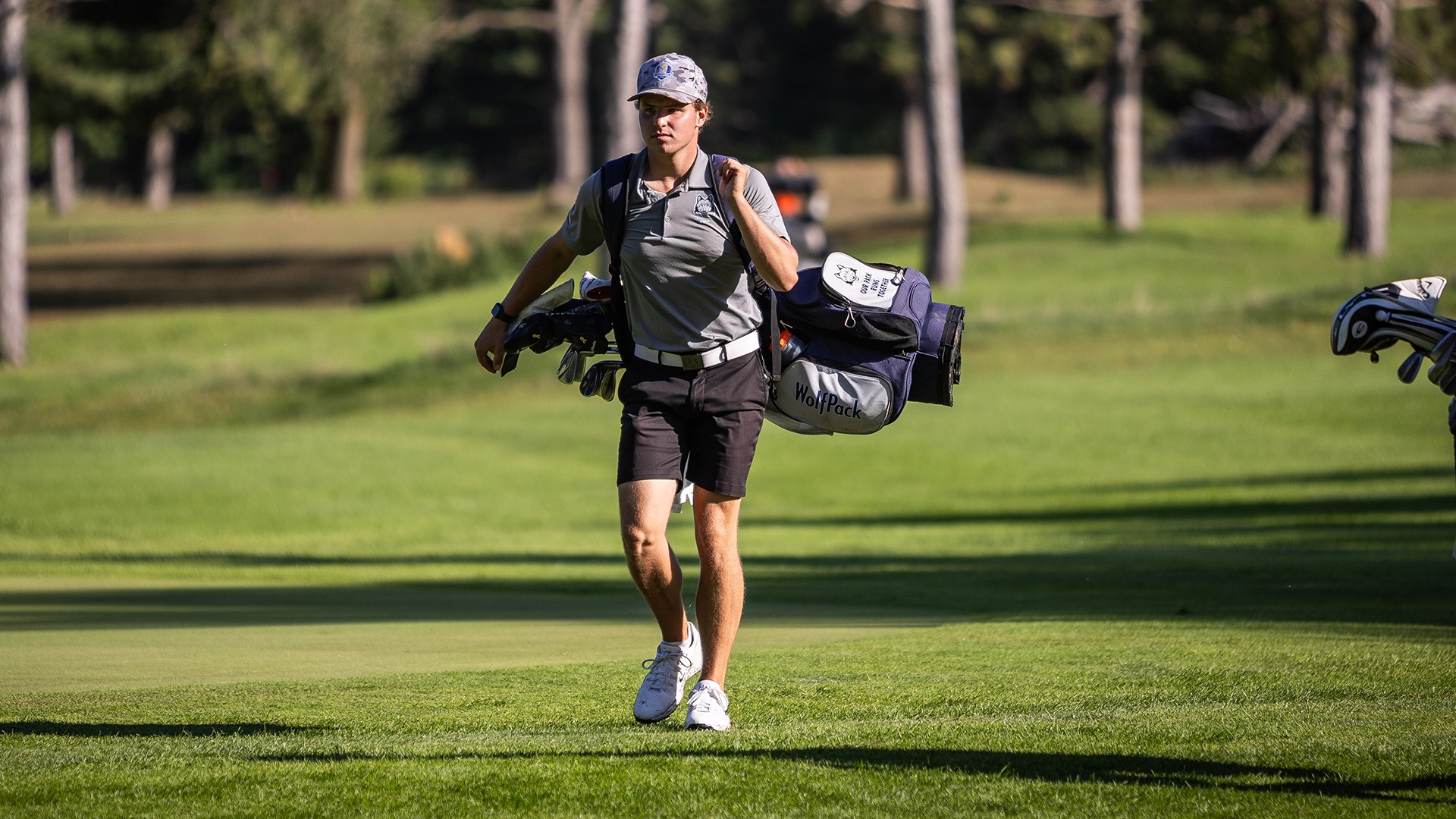 Kaden Zinkle walks up the fairway with his golf back on his back